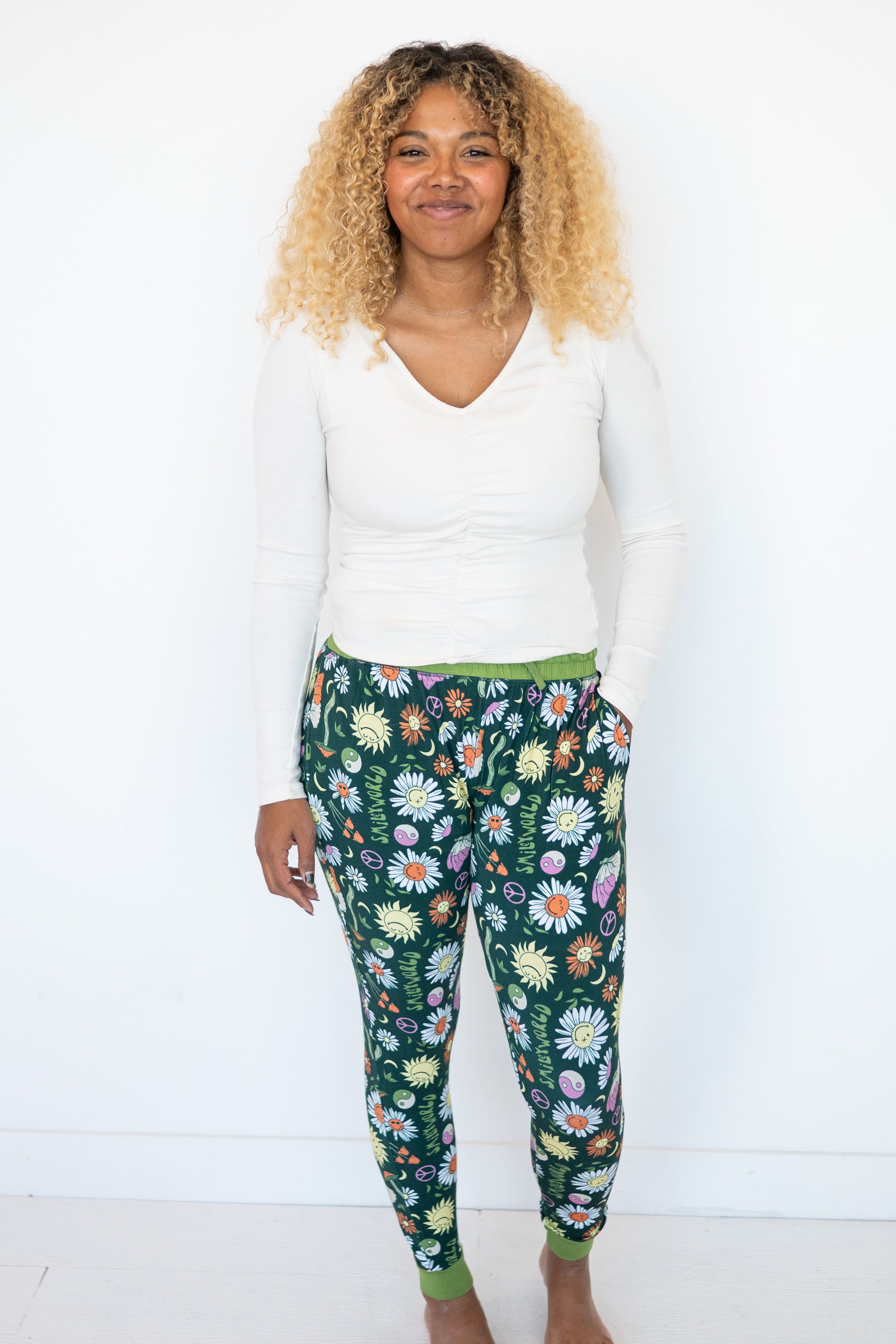 Woman wearing white long-sleeve top and green joggers with a groovy floral print.