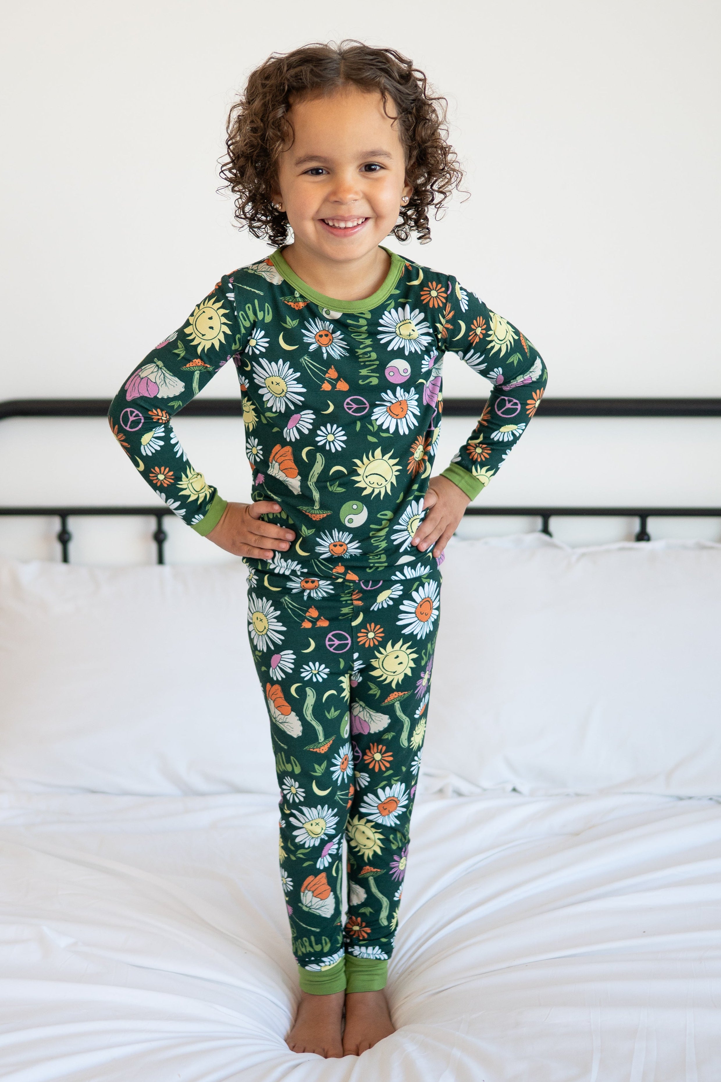 A young girl wears a green pajama set with a groovy floral SmileyWorld print.