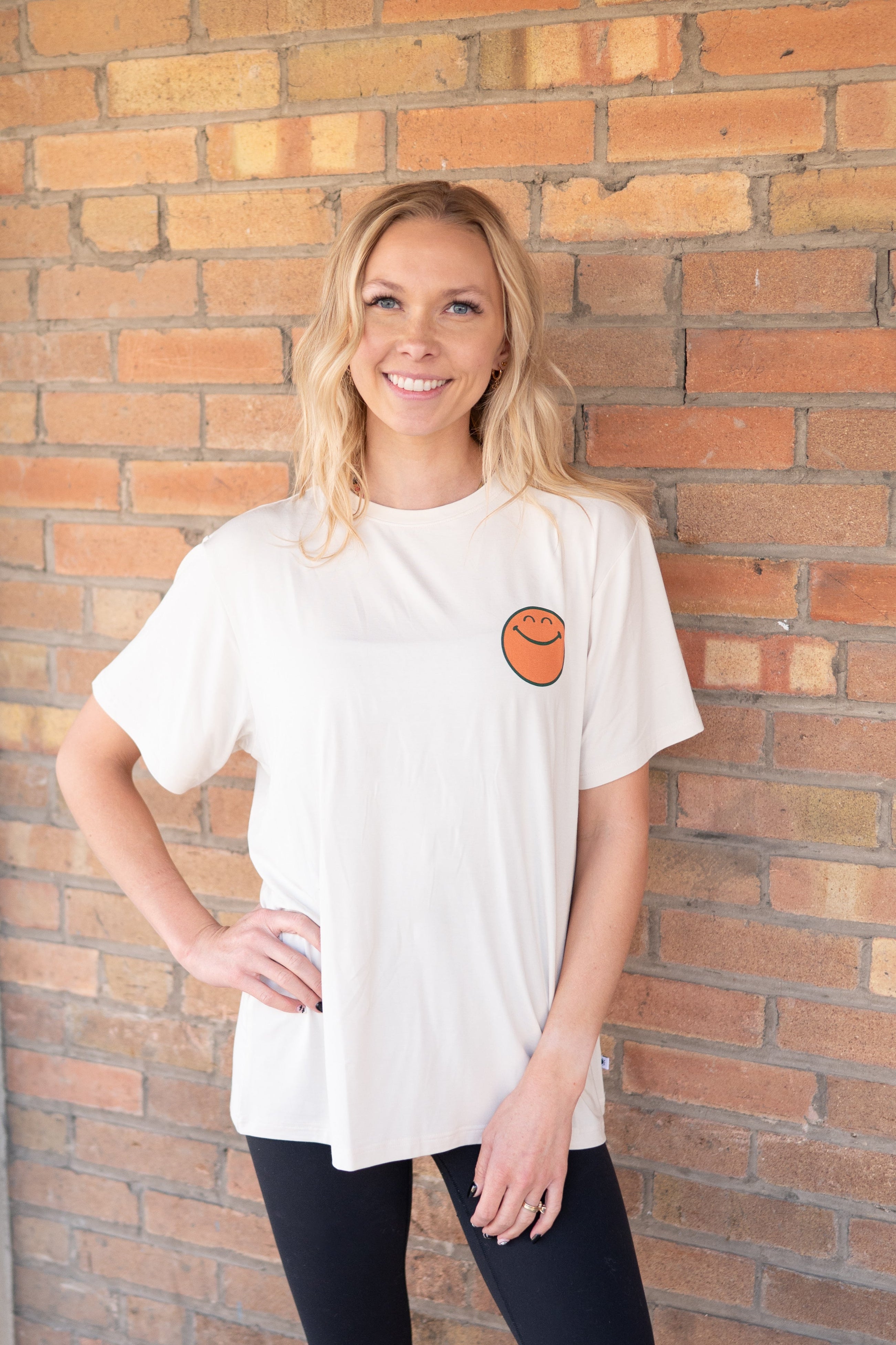 Oversized cream t-shirt with a small orange smiley face graphic on the chest.