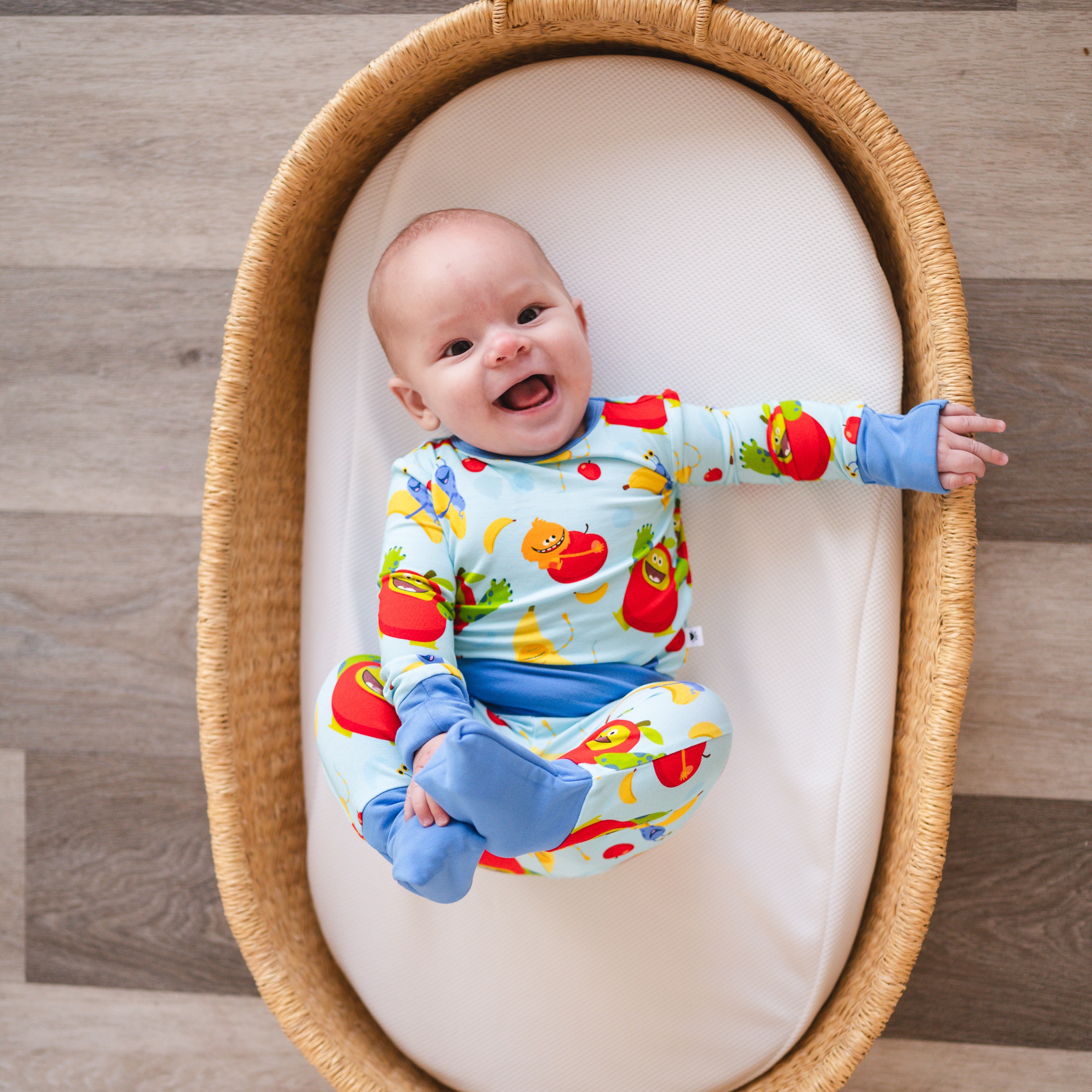 Baby in a light blue pajama set with apples and bananas.