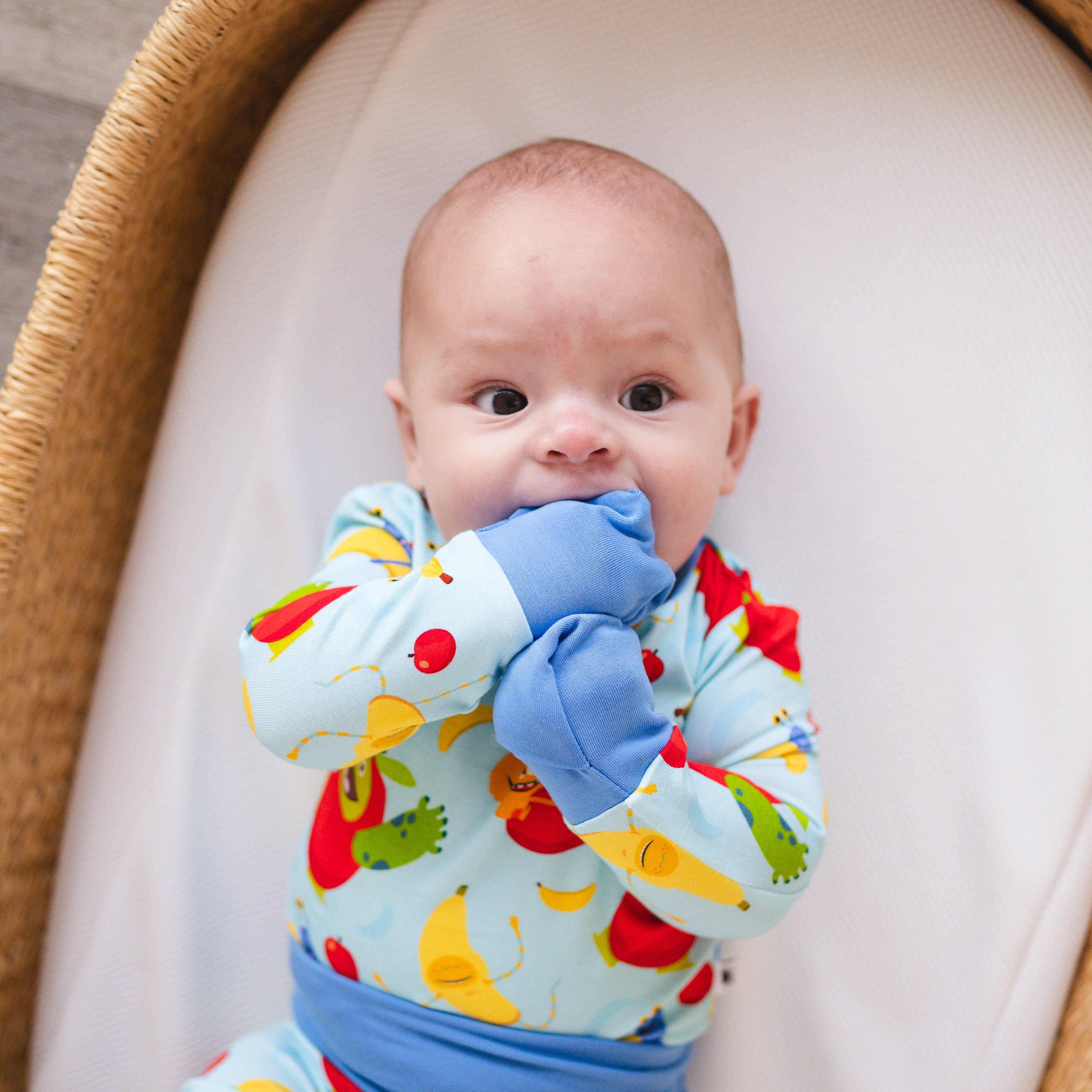Baby in a light blue pajama set with apples and bananas.