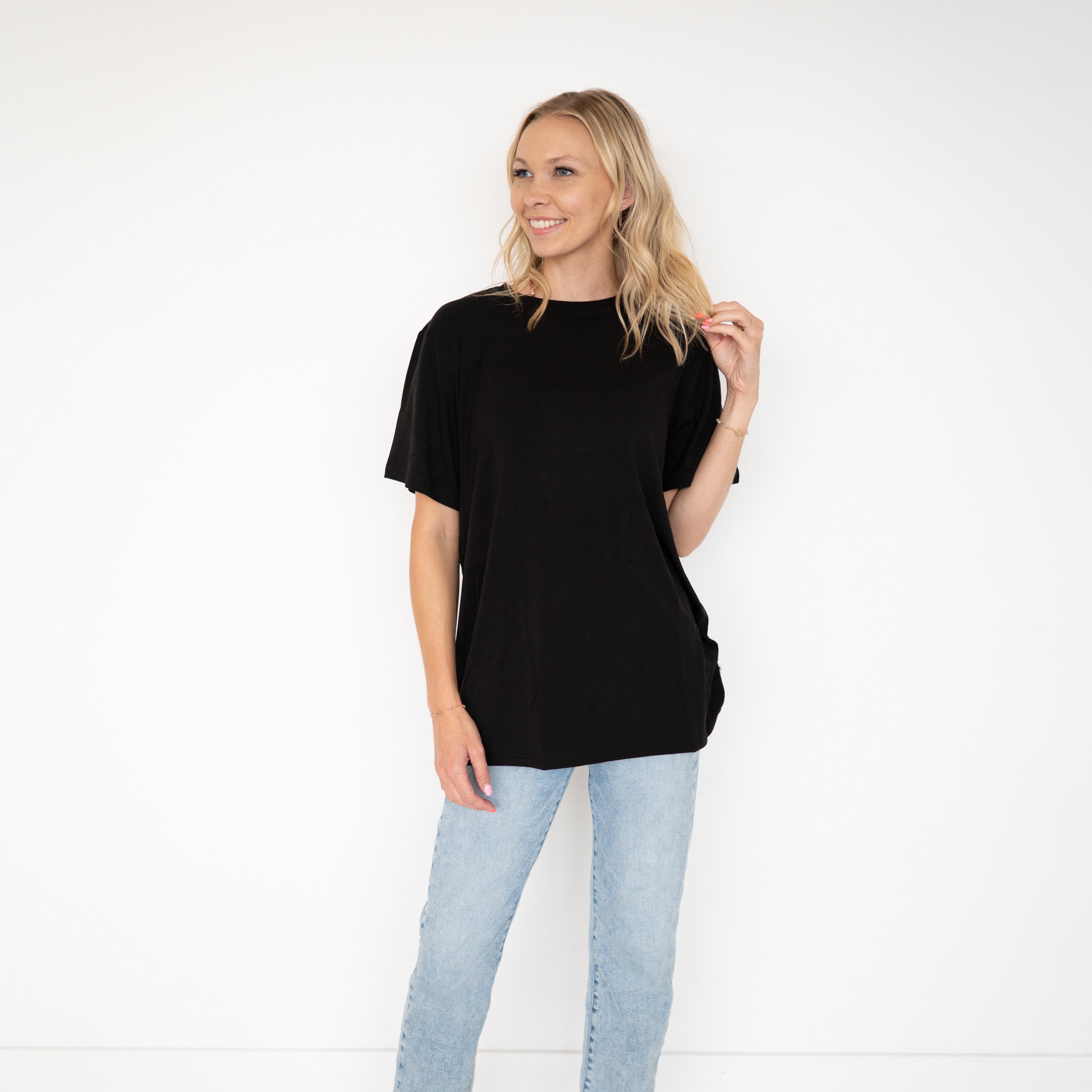 A woman wears a black oversized bamboo t-shirt and light wash jeans.