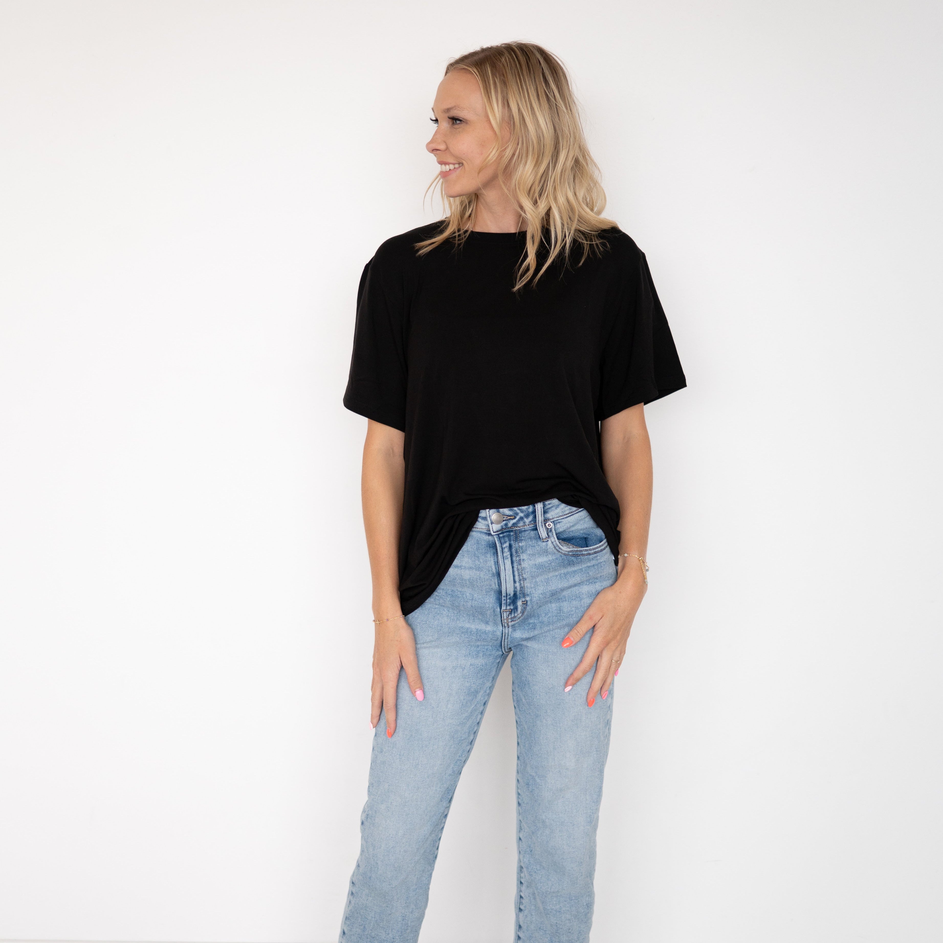 A woman wears an oversized black bamboo t-shirt and light wash jeans.