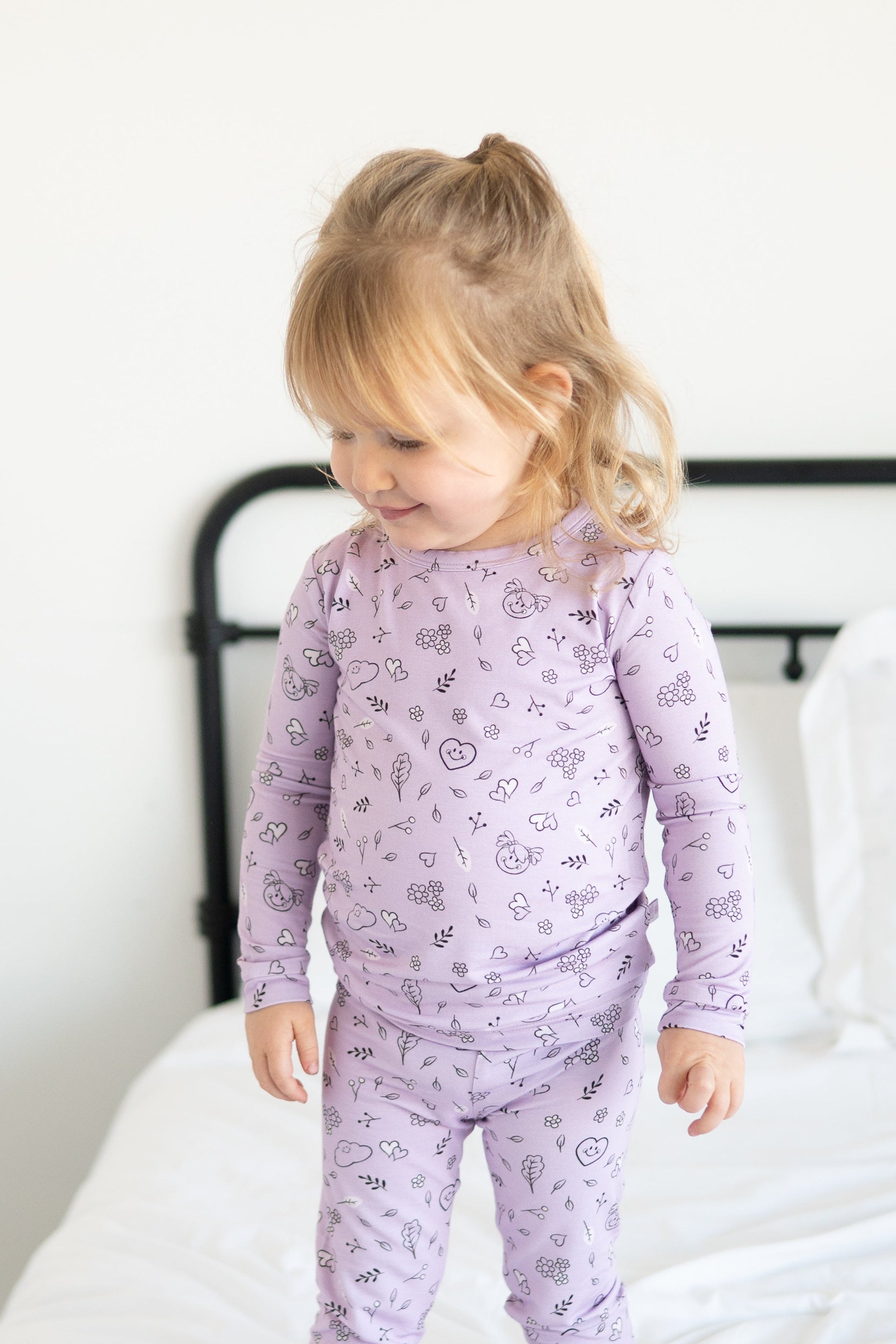 A young girl wears a lilac pajama set with a doodle print.