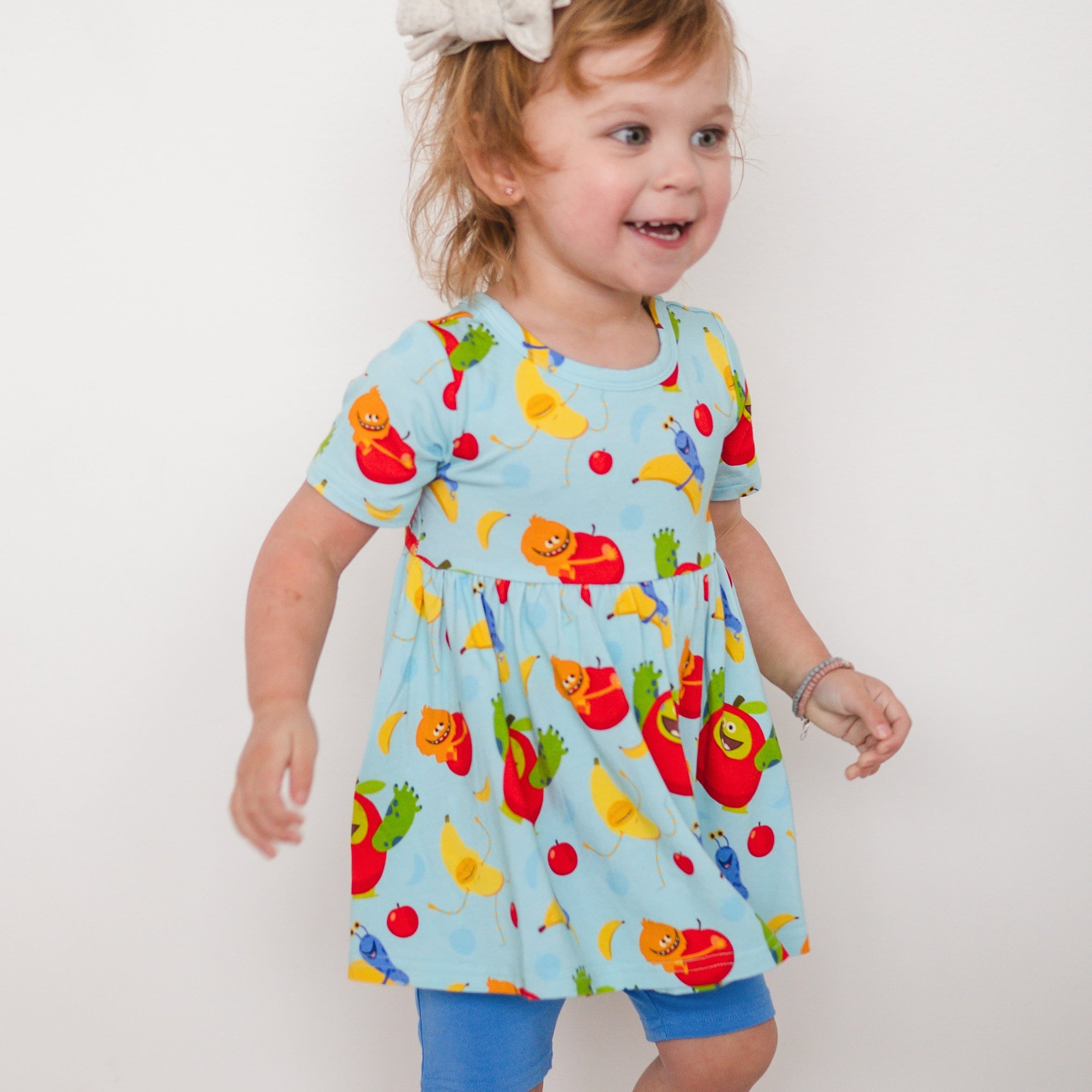 A light blue peplum top with a playful apples and bananas print.