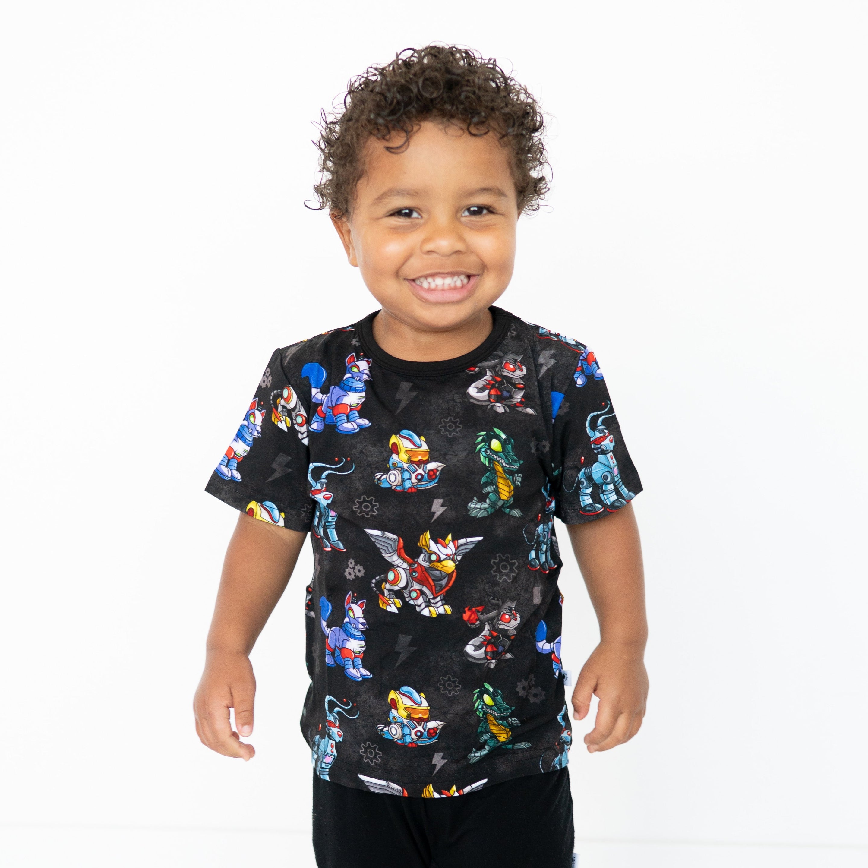 A young boy smiles wearing a black t-shirt with a Neopets robot pattern.