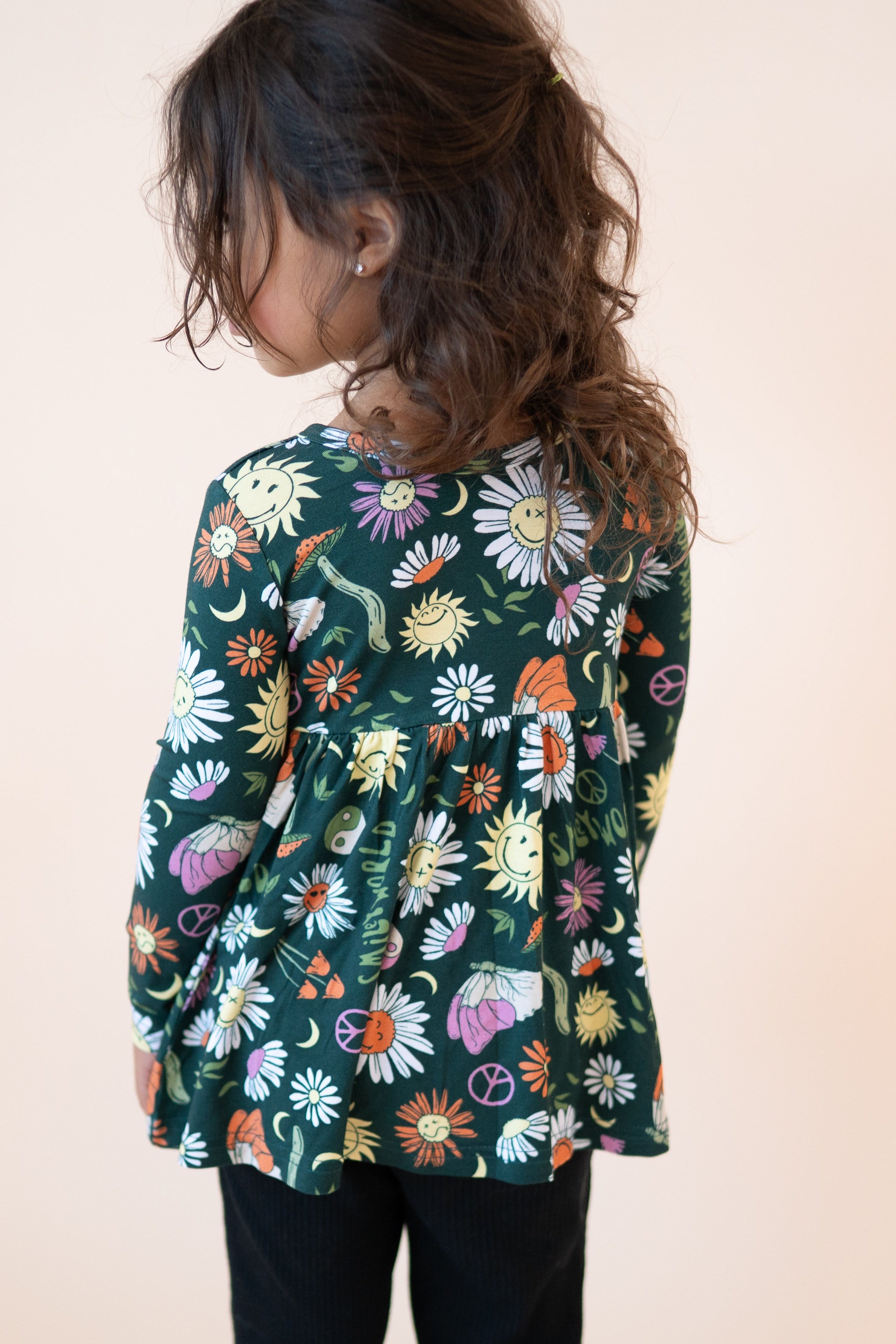 Girl's long sleeve peplum top with a green groovy floral SmileyWorld print.