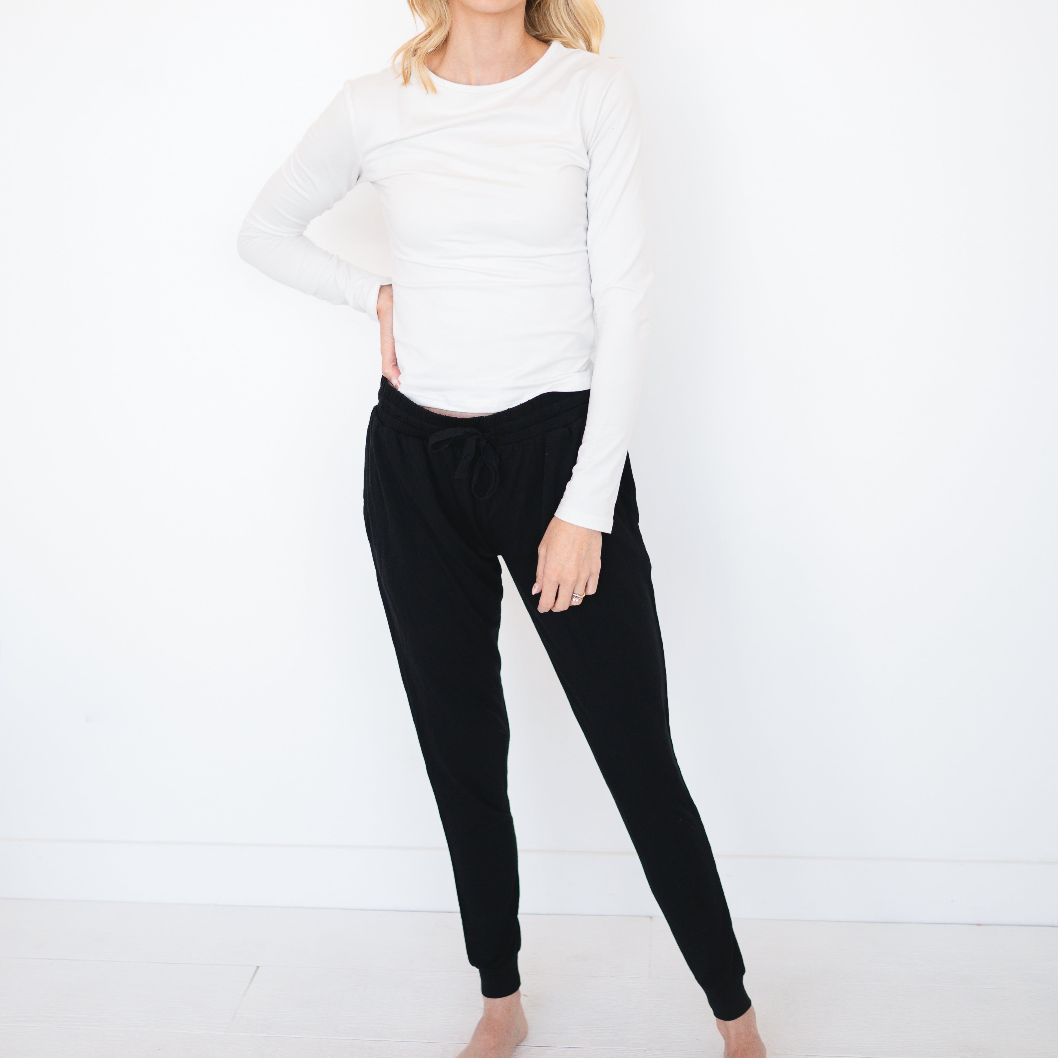 Woman wearing a white long-sleeve shirt and black bamboo joggers.