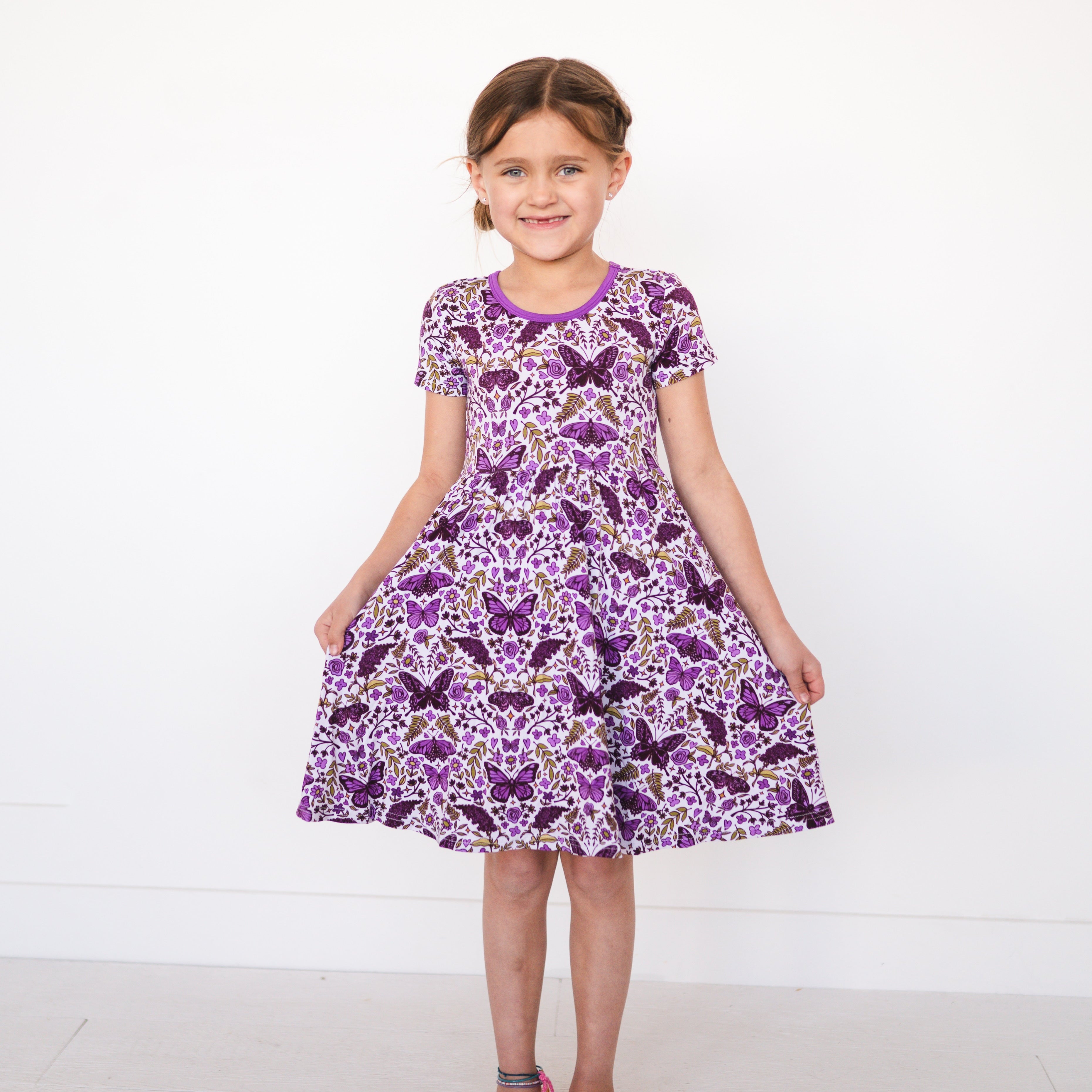 Girl in a purple butterfly garden print dress.