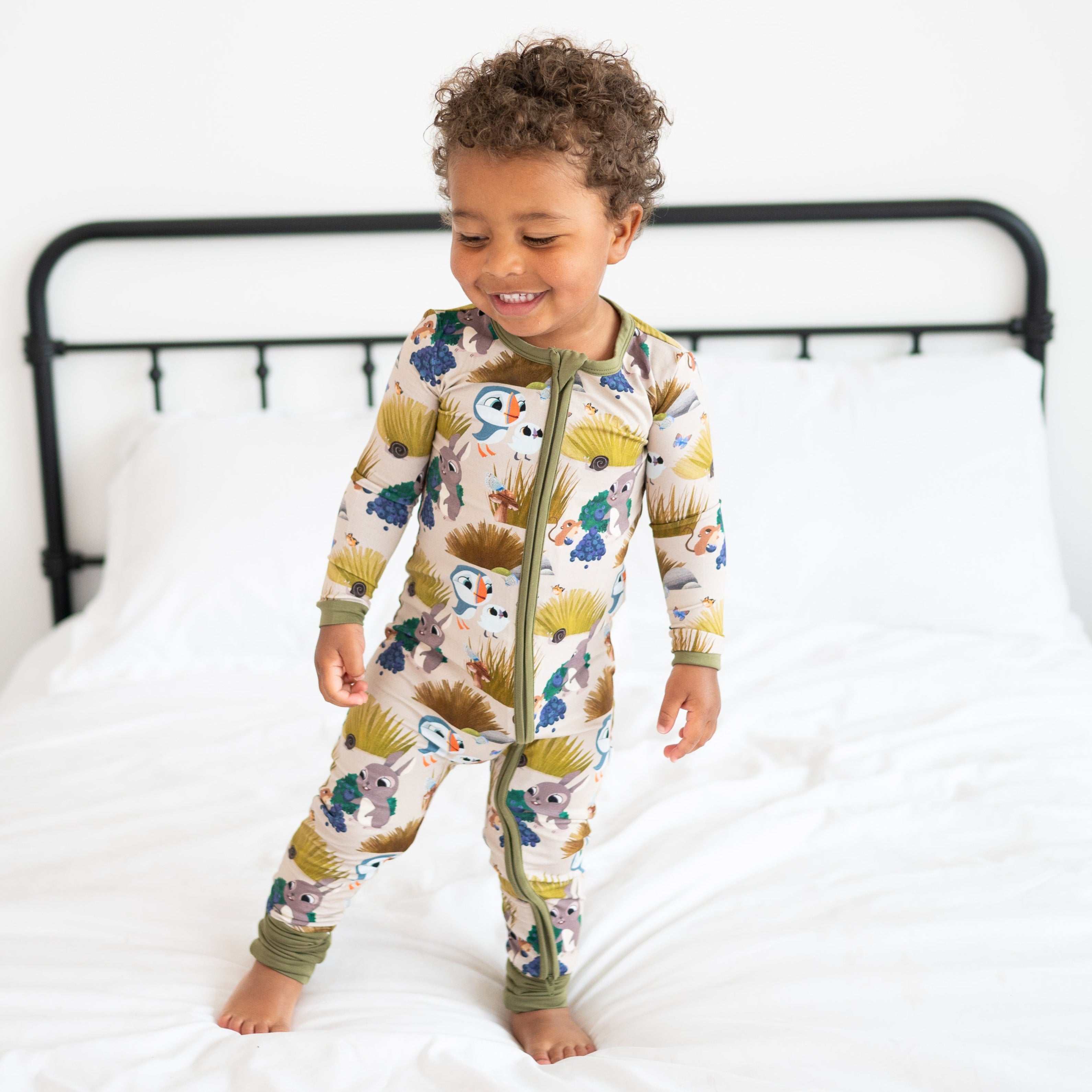 A toddler boy wears a tan bamboo pajama set with a Puffin Rock print.