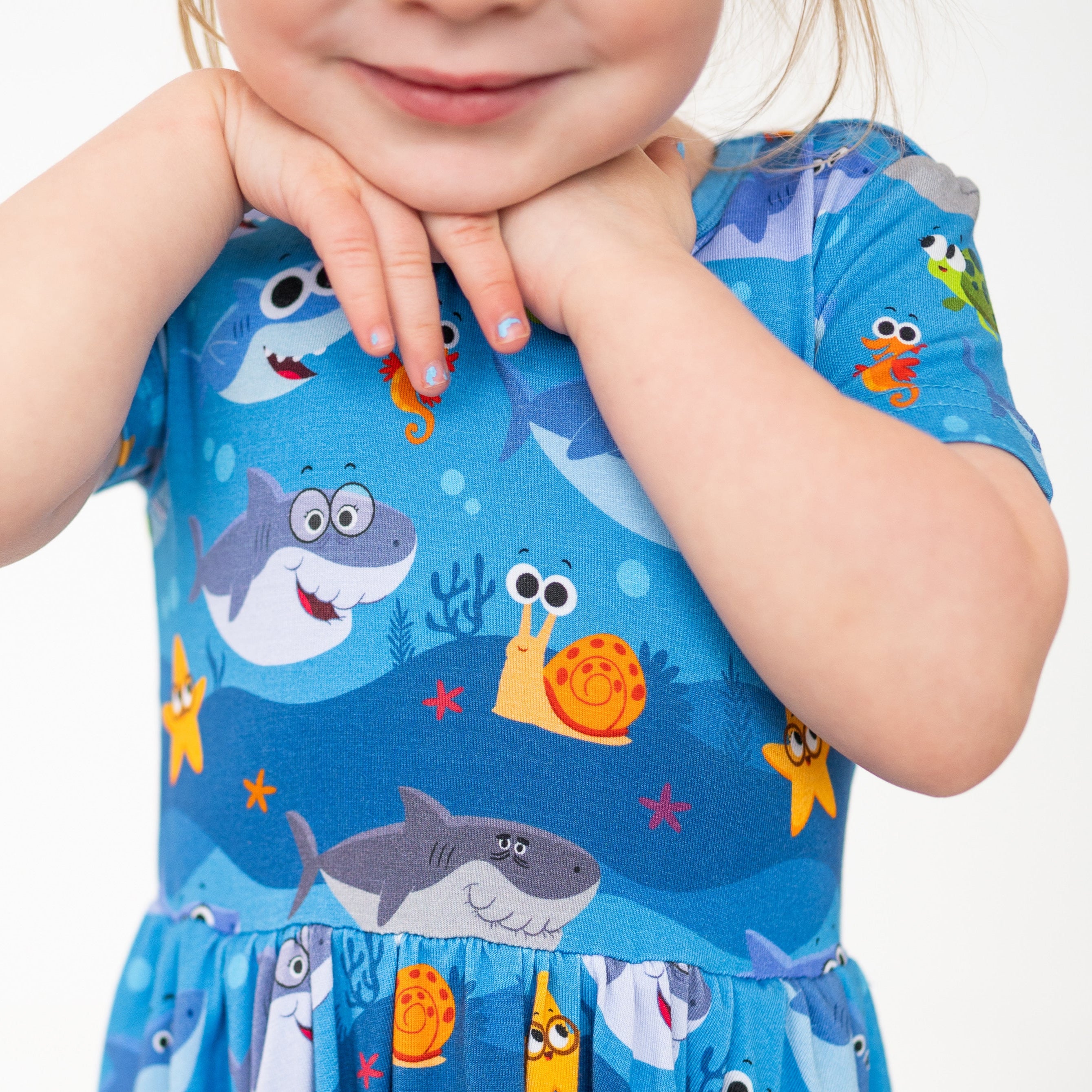 A blue dress with a Baby Shark print, featuring sharks, a snail, and starfish.