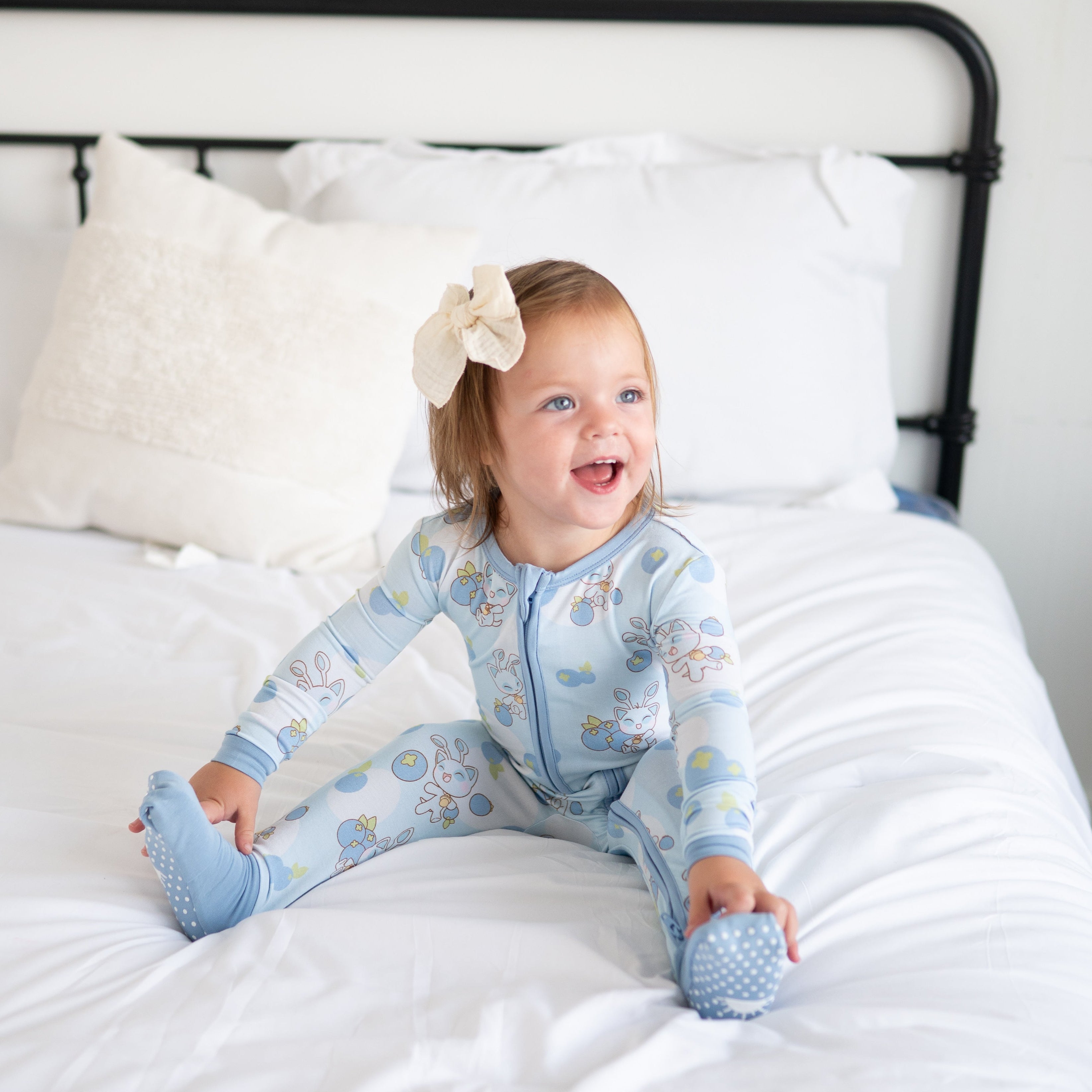 Baby in blue Neopets blueberry print zip pajamas with a bow.