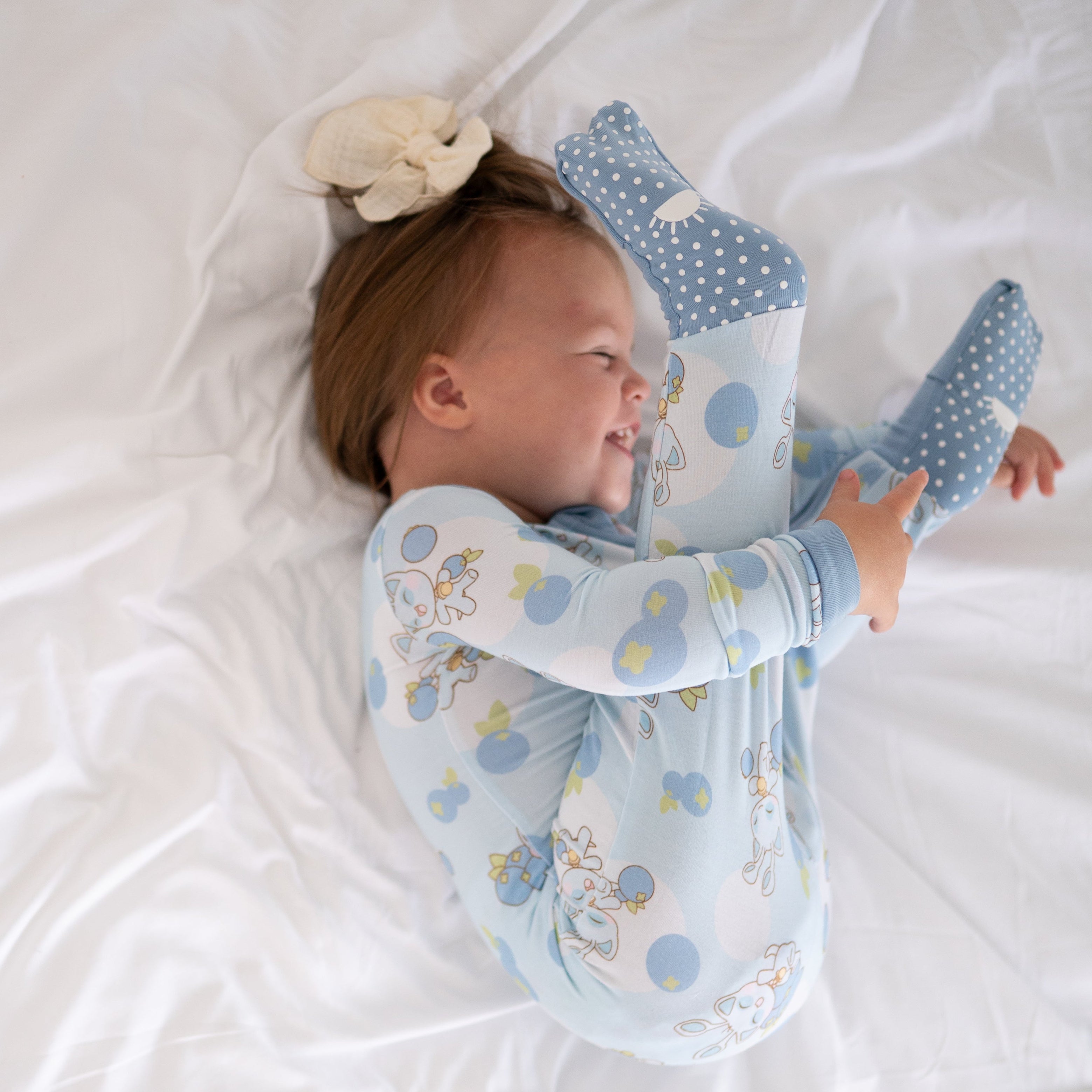 Baby in blue Neopets blueberry pajamas with feet up.