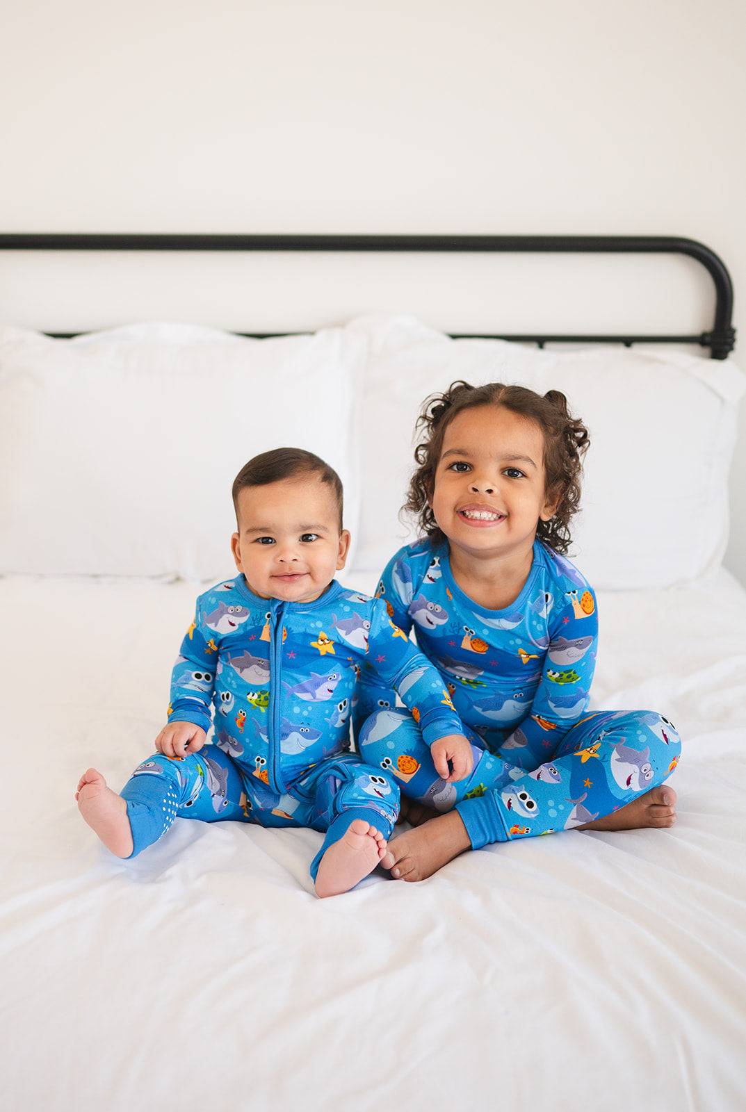 Two children in blue bamboo pajamas with a baby shark print.