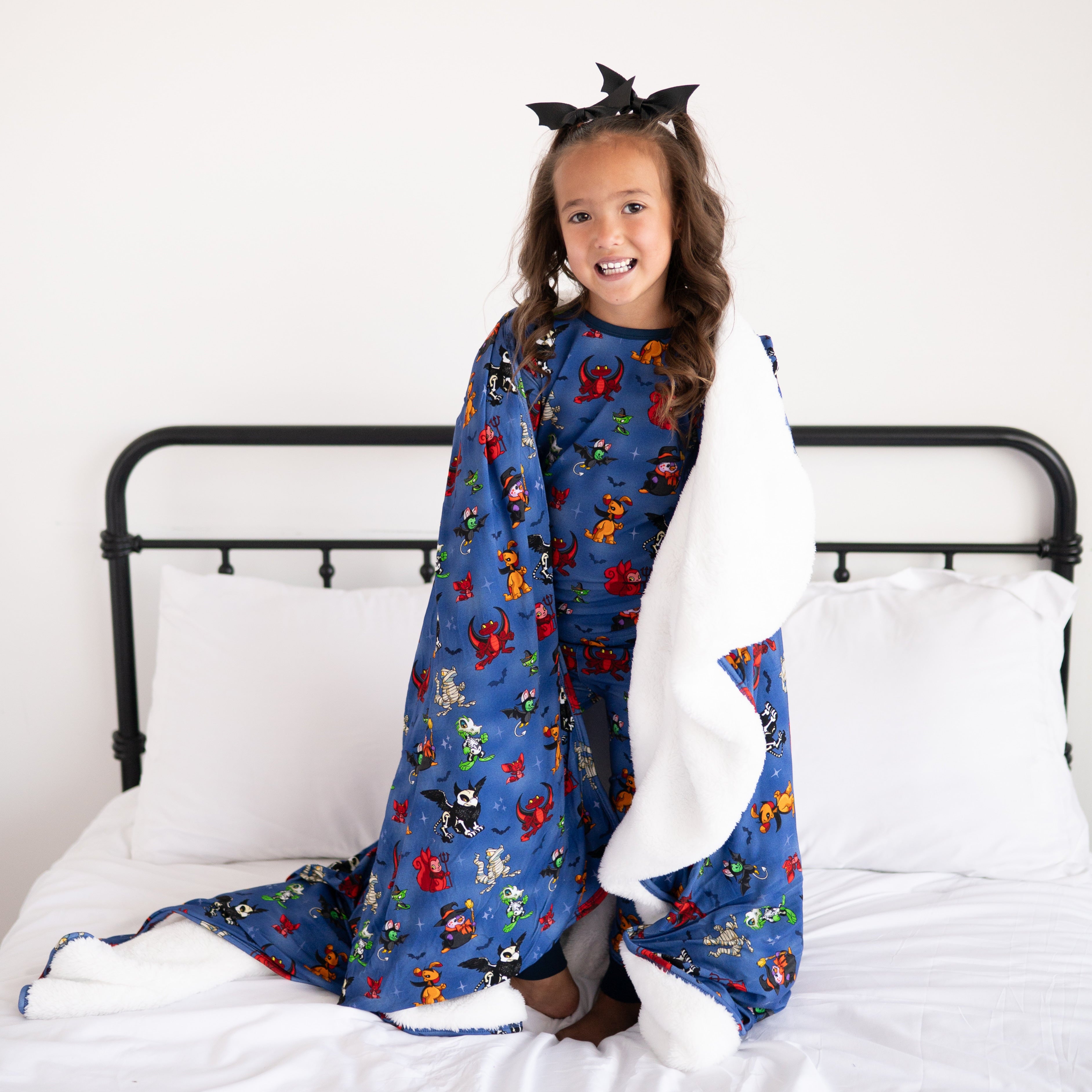 A young girl wearing a Halloween-themed blanket with Neopets characters.