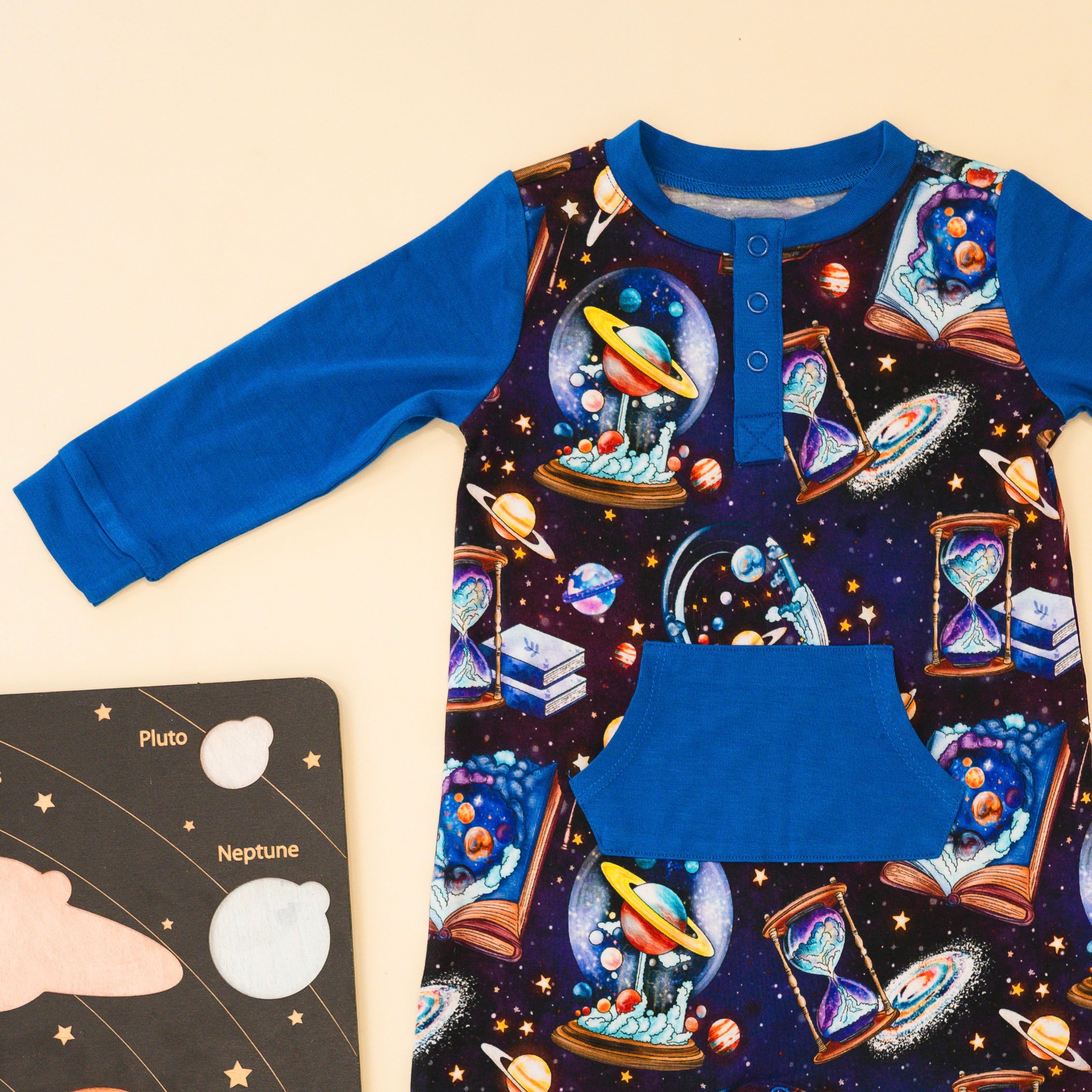 A long-sleeved blue and space-themed romper with a pocket.