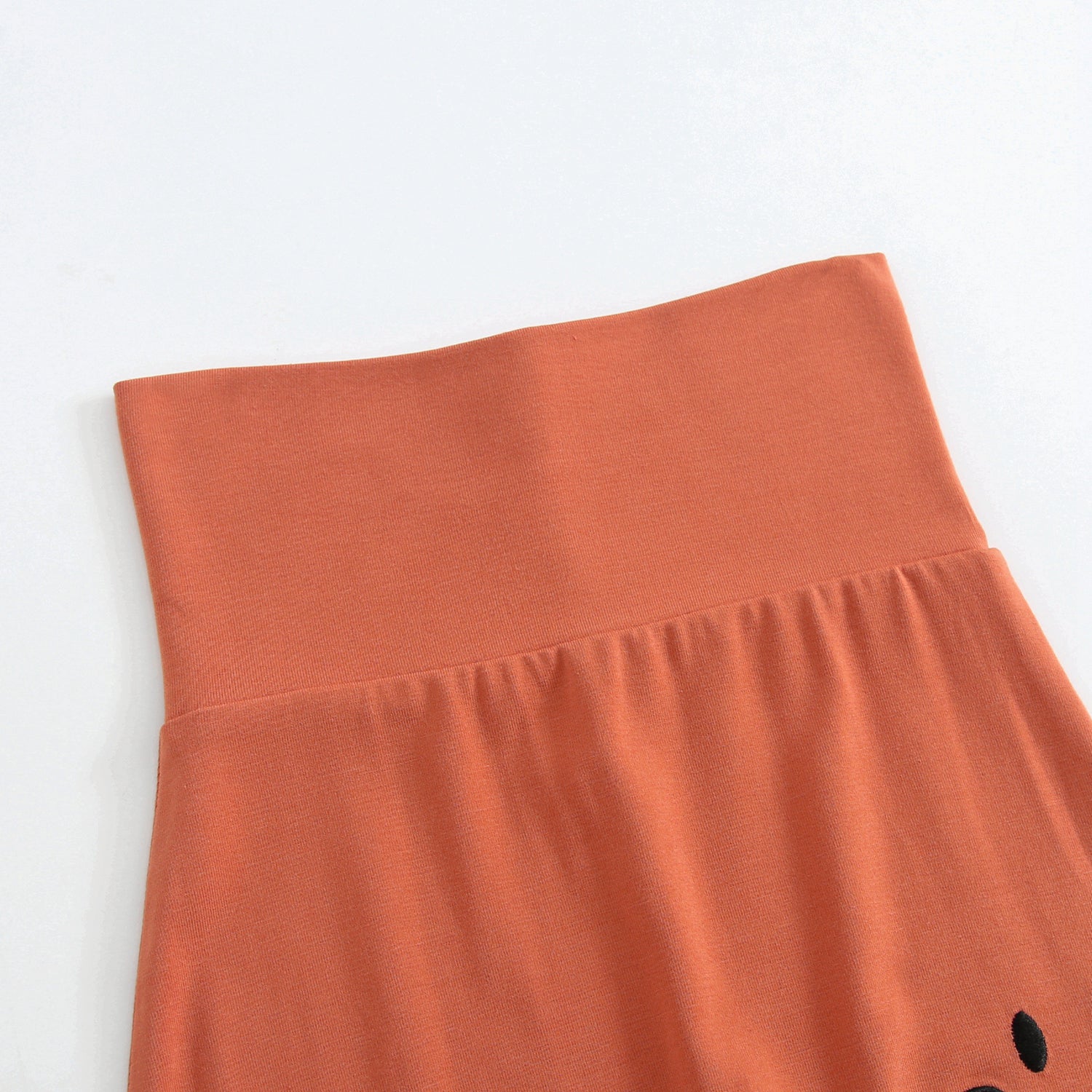 Orange bamboo pants with a fold-over waistband and a small embroidered smiley face.