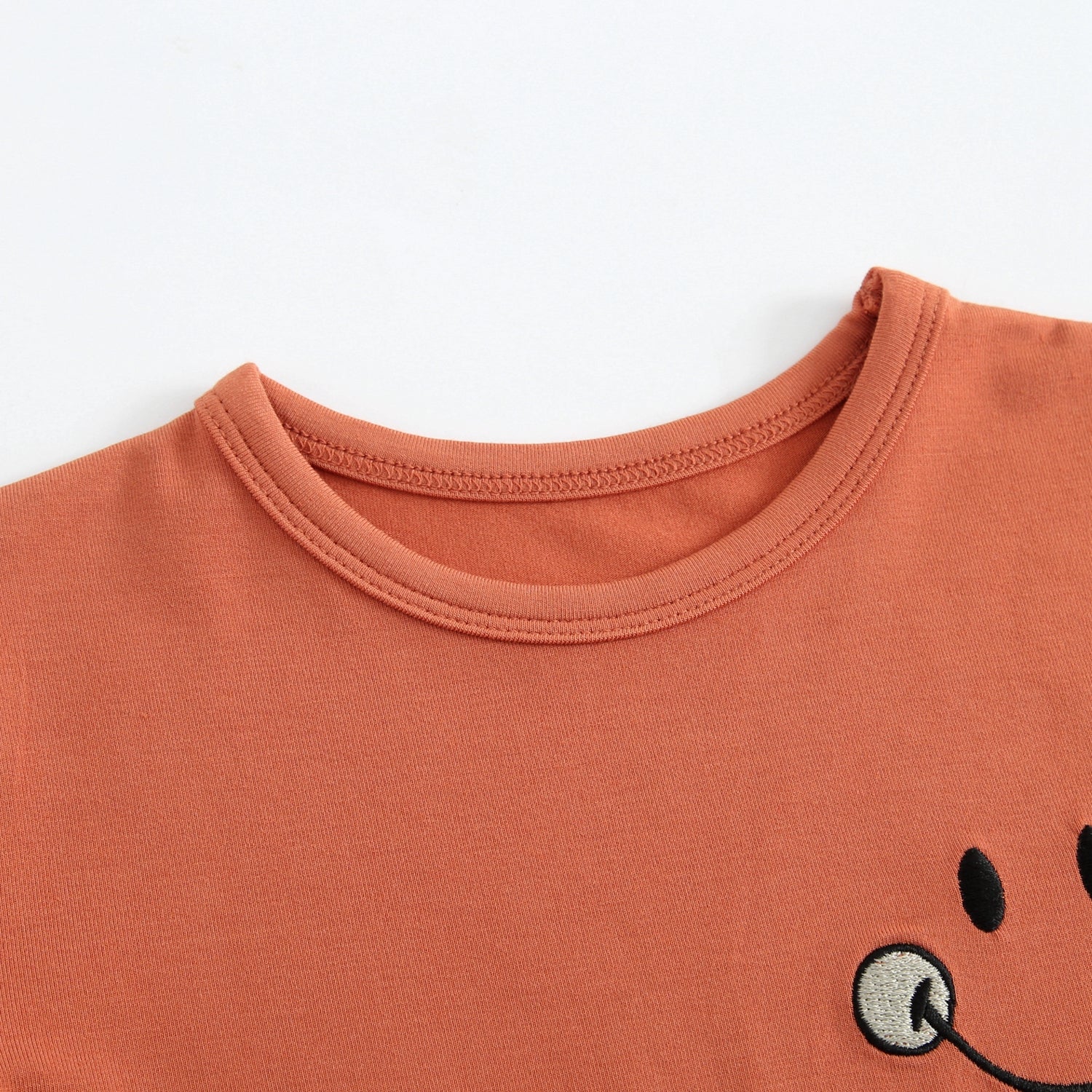 Rust colored t-shirt with embroidered smiley face.