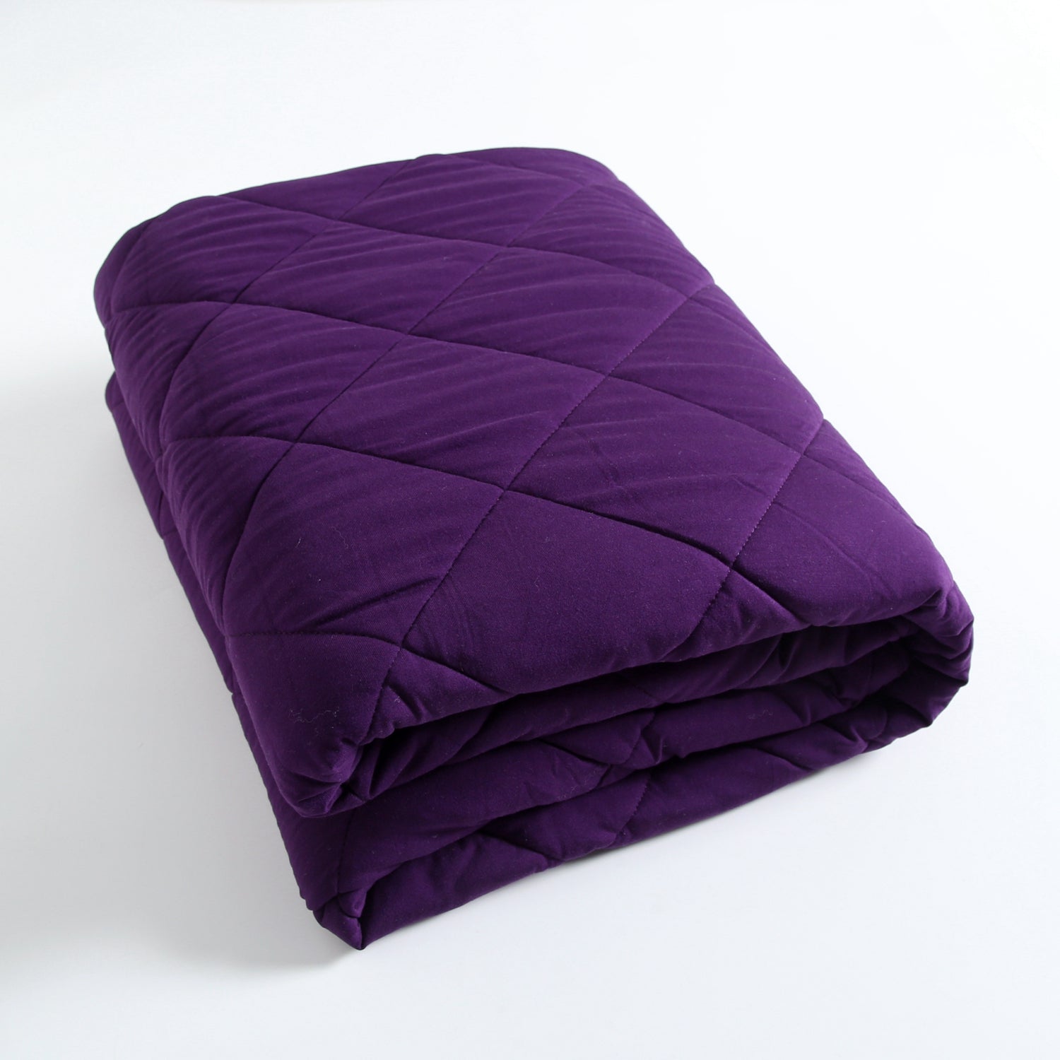 A folded, quilted purple blanket with a diamond pattern.