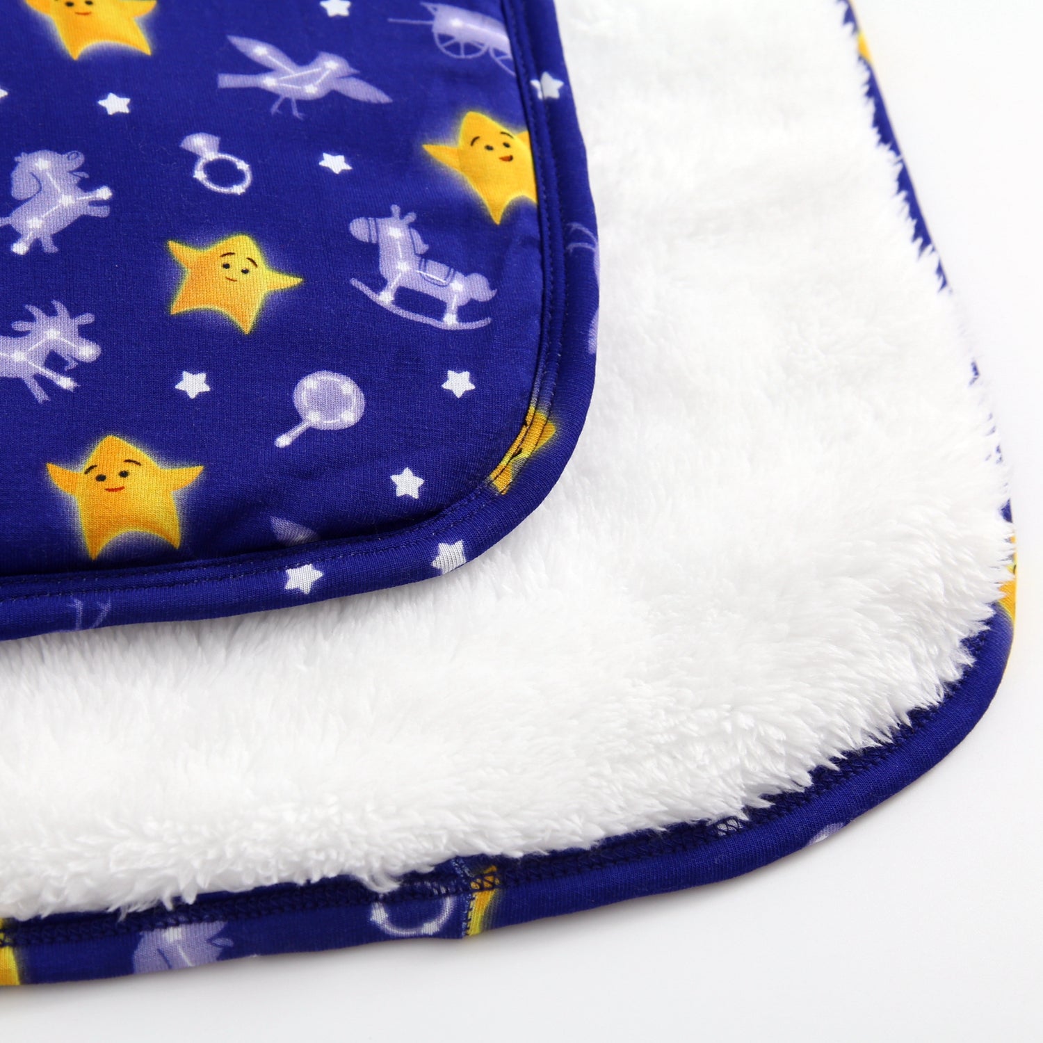A blue blanket with yellow stars and white constellations on a white plush background.