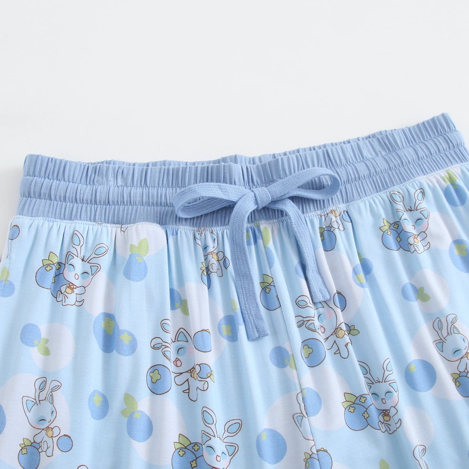 Light blue joggers with a drawstring waist and a pattern of cute blue bunnies holding blueberries.