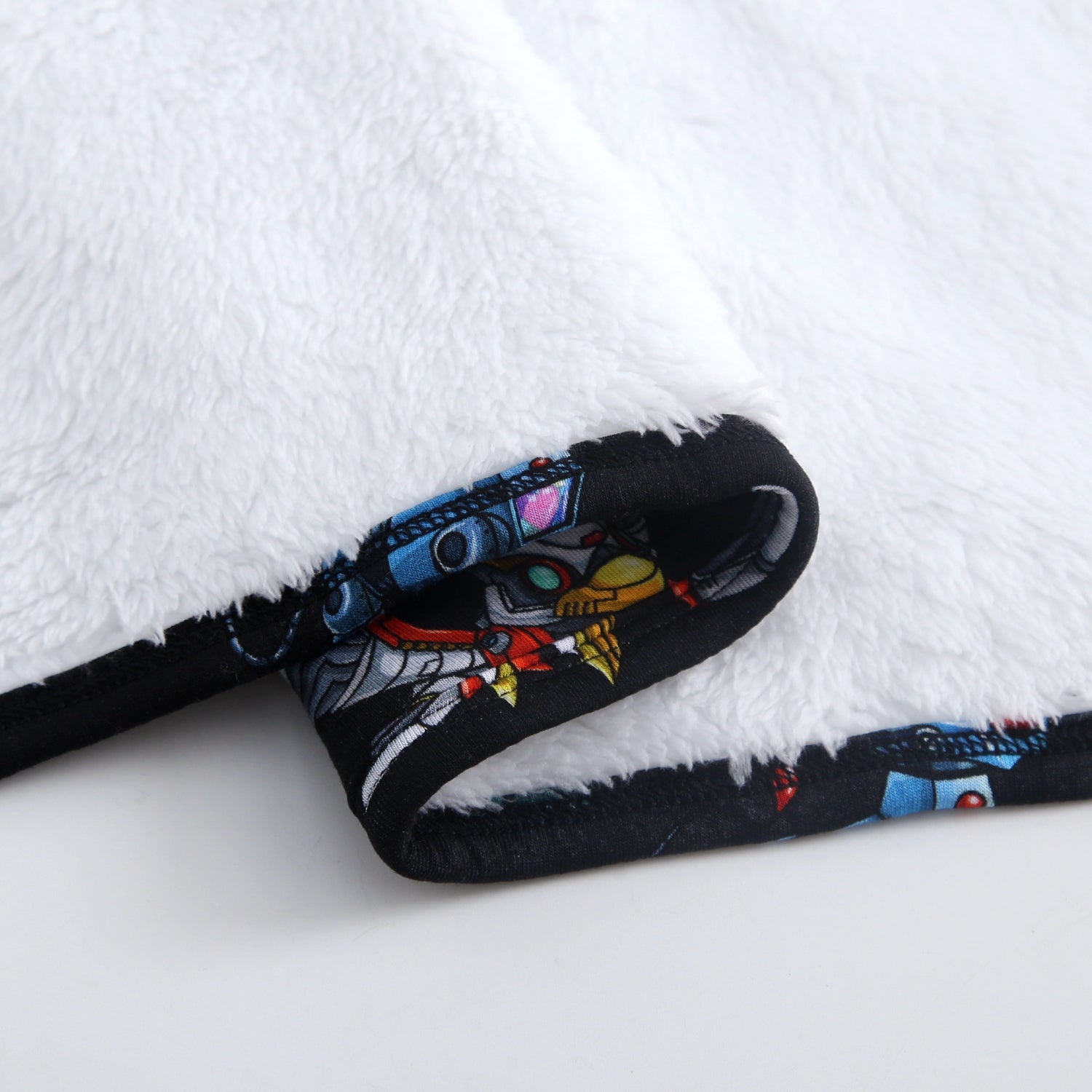 White plush blanket with a Neopets robot print trim.