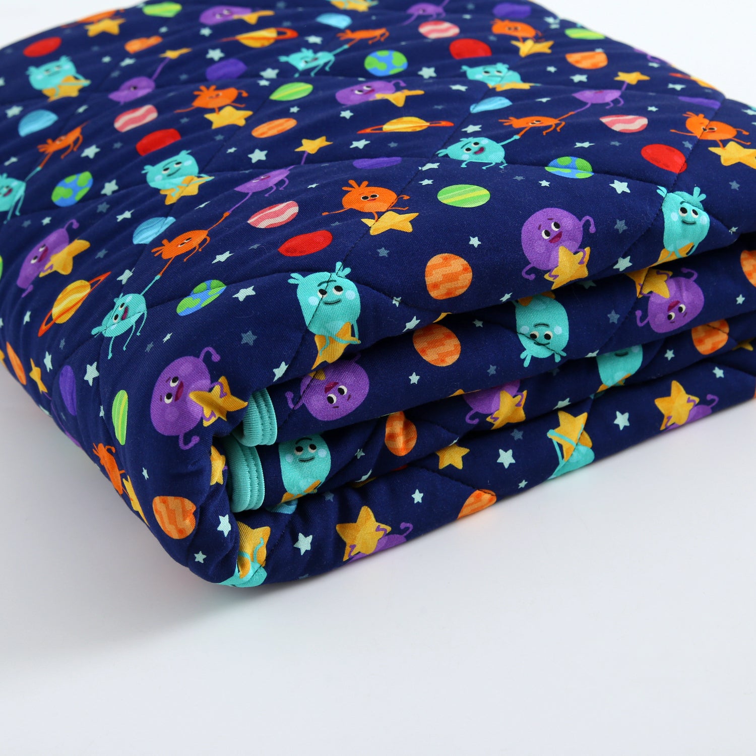 A quilted blanket with a dark blue background and a pattern of cartoon aliens, planets, and stars.