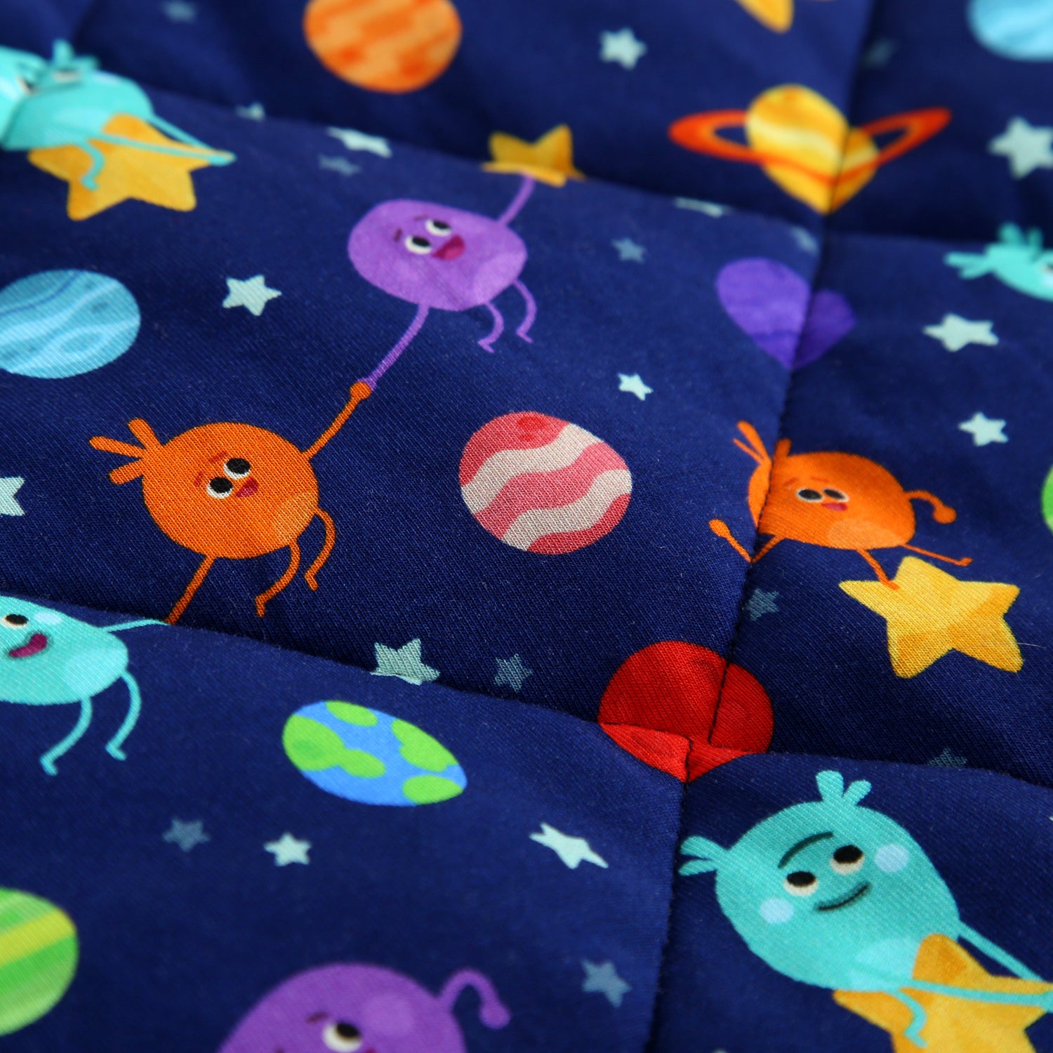 A quilted blanket with a dark blue space-themed pattern featuring cartoon aliens and planets.