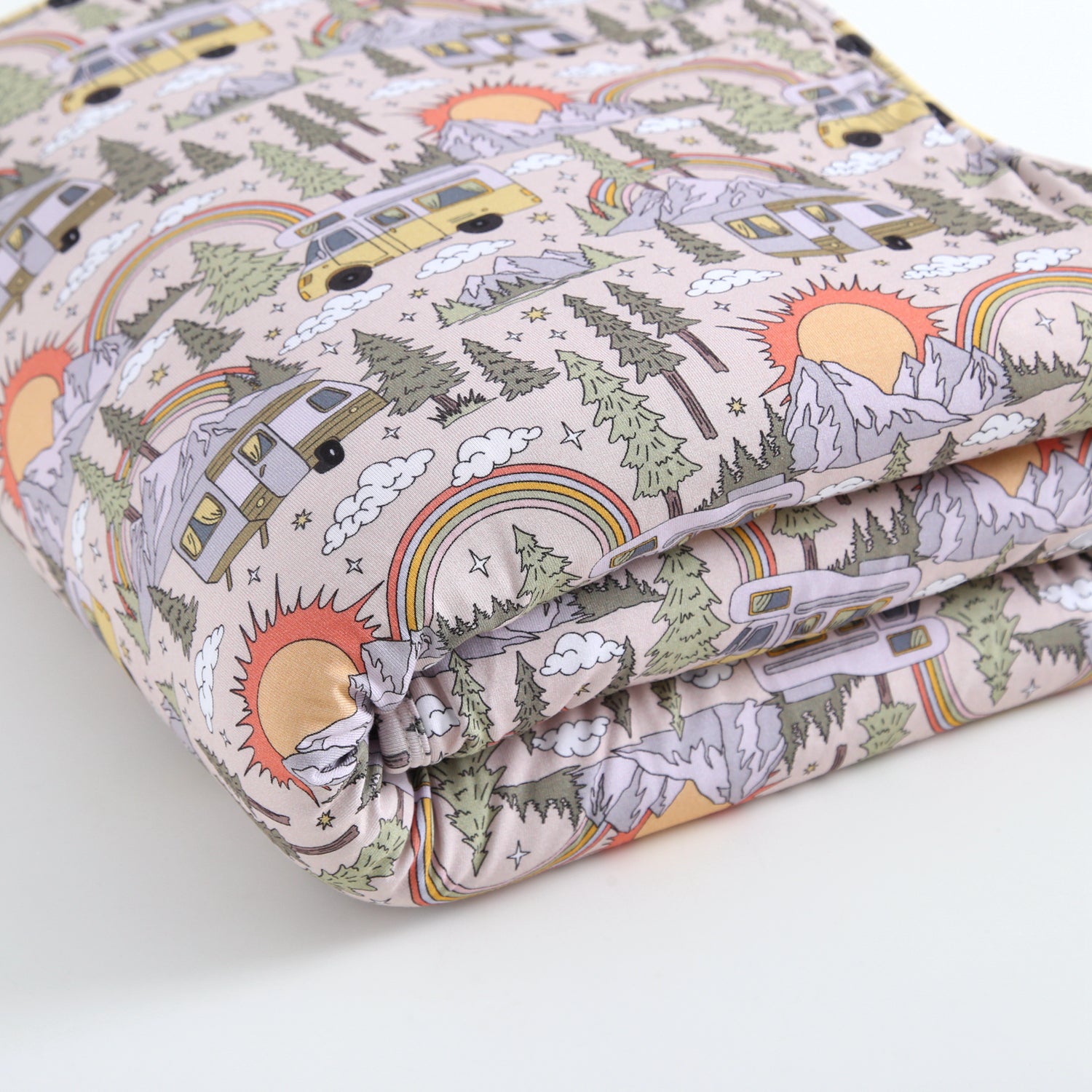 A folded plush blanket with a vintage camper, mountain, and rainbow pattern.