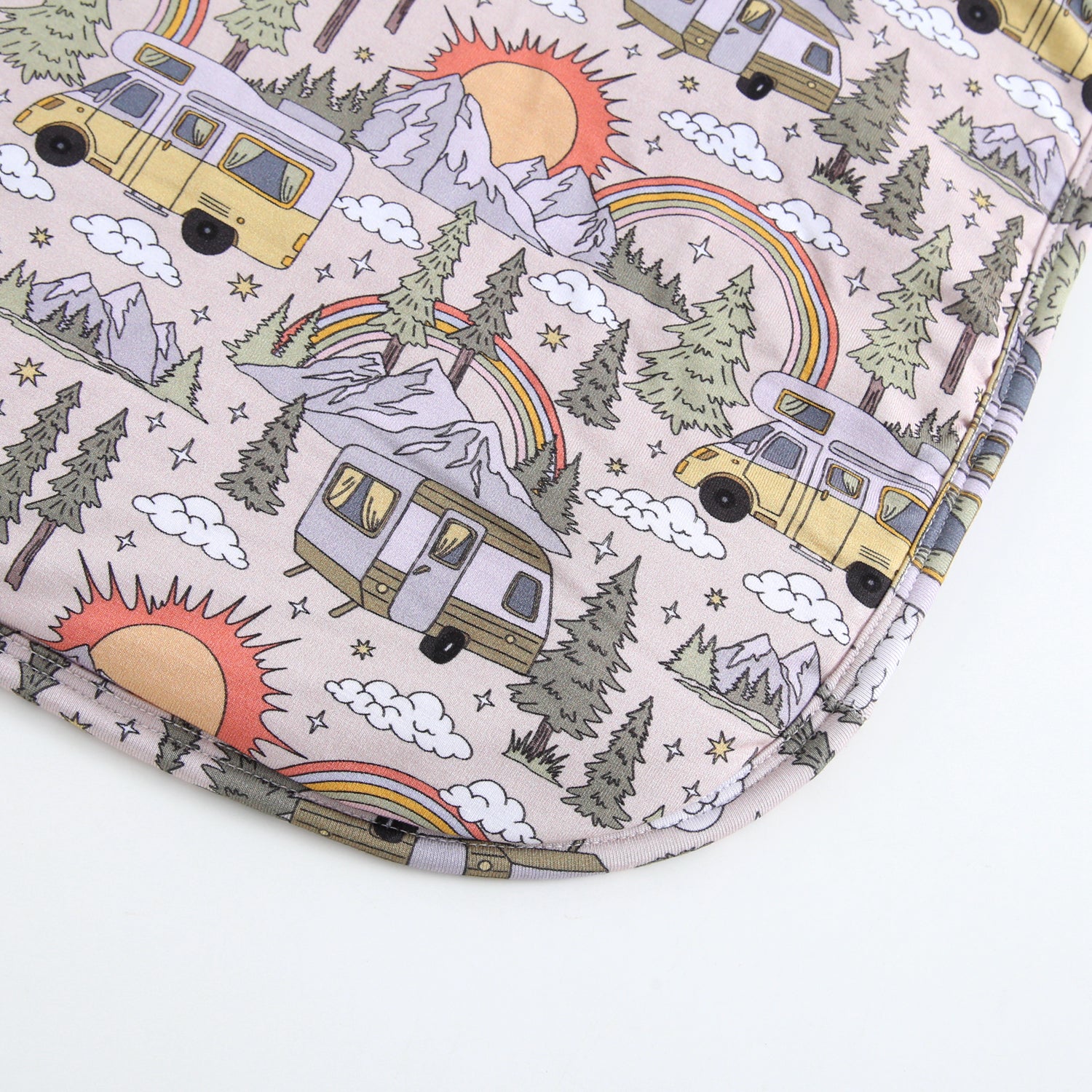 A plush blanket with a vintage camper, mountain, and rainbow pattern.