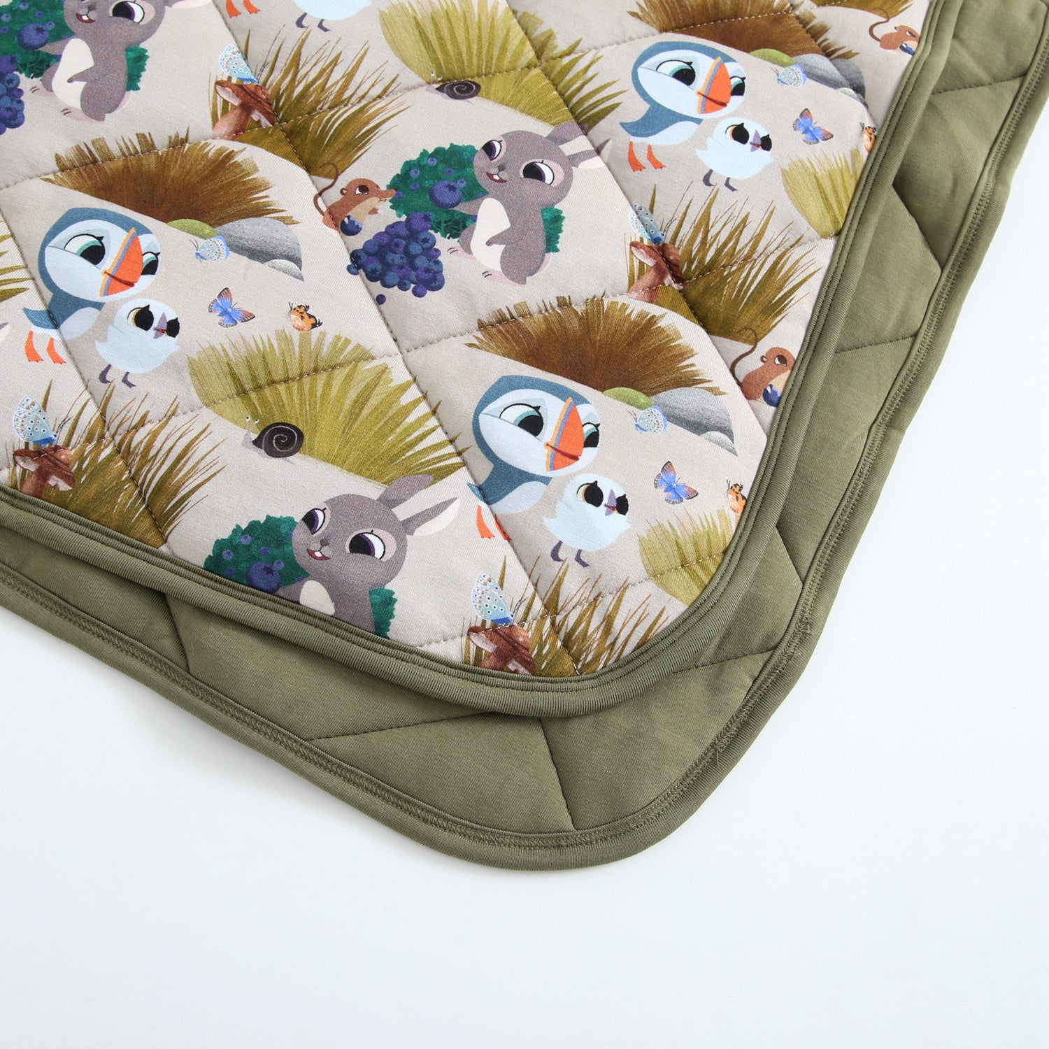 A quilted blanket with a Puffin Rock™ pattern and a green border.