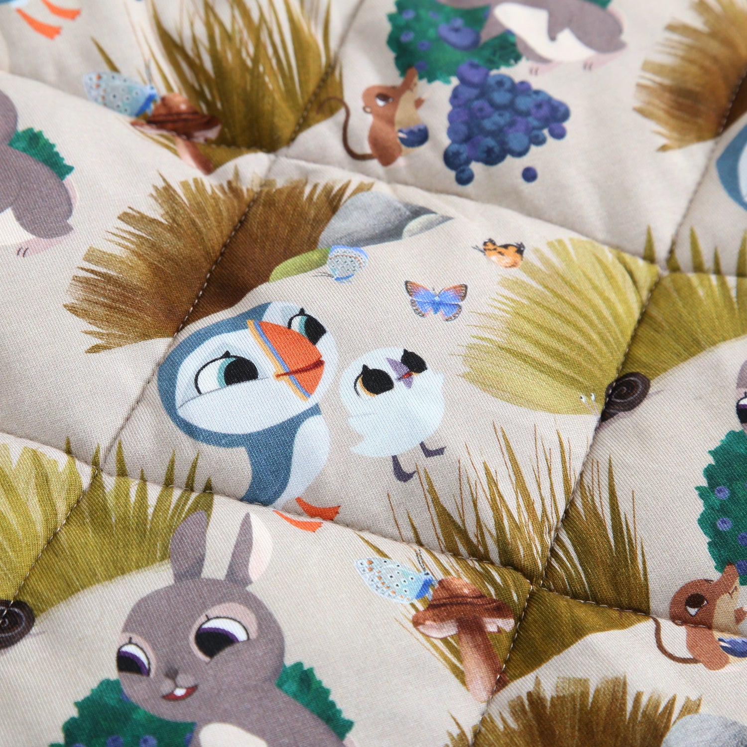 A quilted blanket with a Puffin Rock™ pattern featuring puffins, rabbits, and other woodland creatures.
