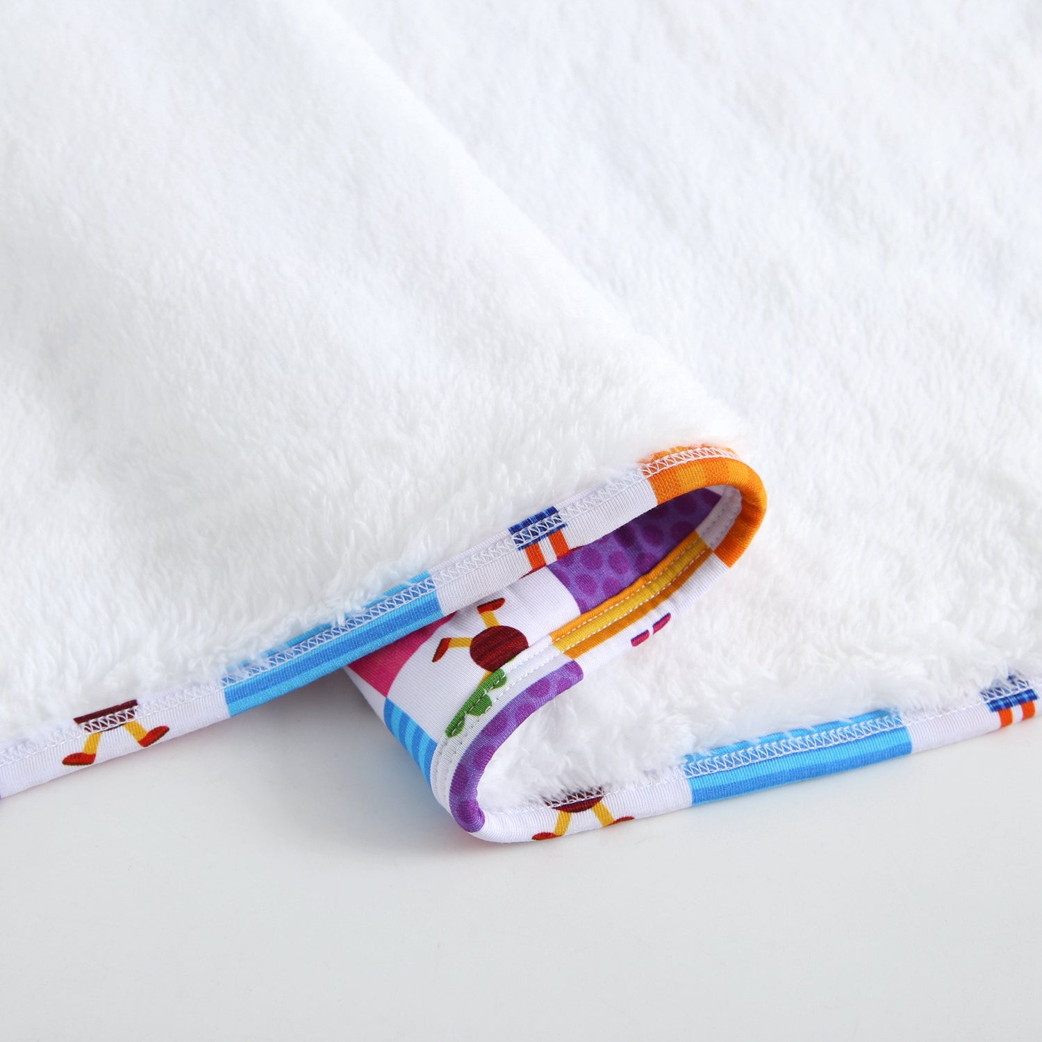 White plush blanket with a colorful trim featuring cartoon characters.