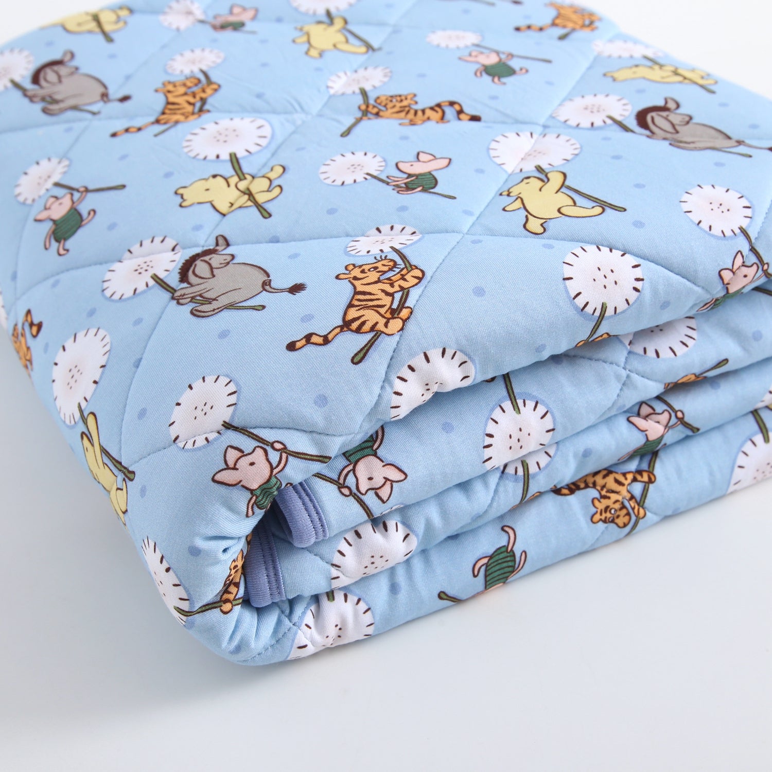 A light blue quilted blanket with a Winnie the Pooh character print.