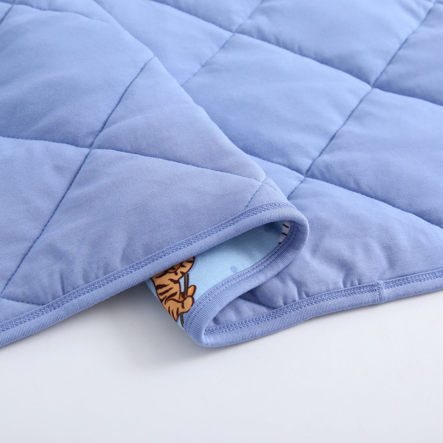 A light blue quilted blanket with a cartoon tiger pattern visible on the underside.