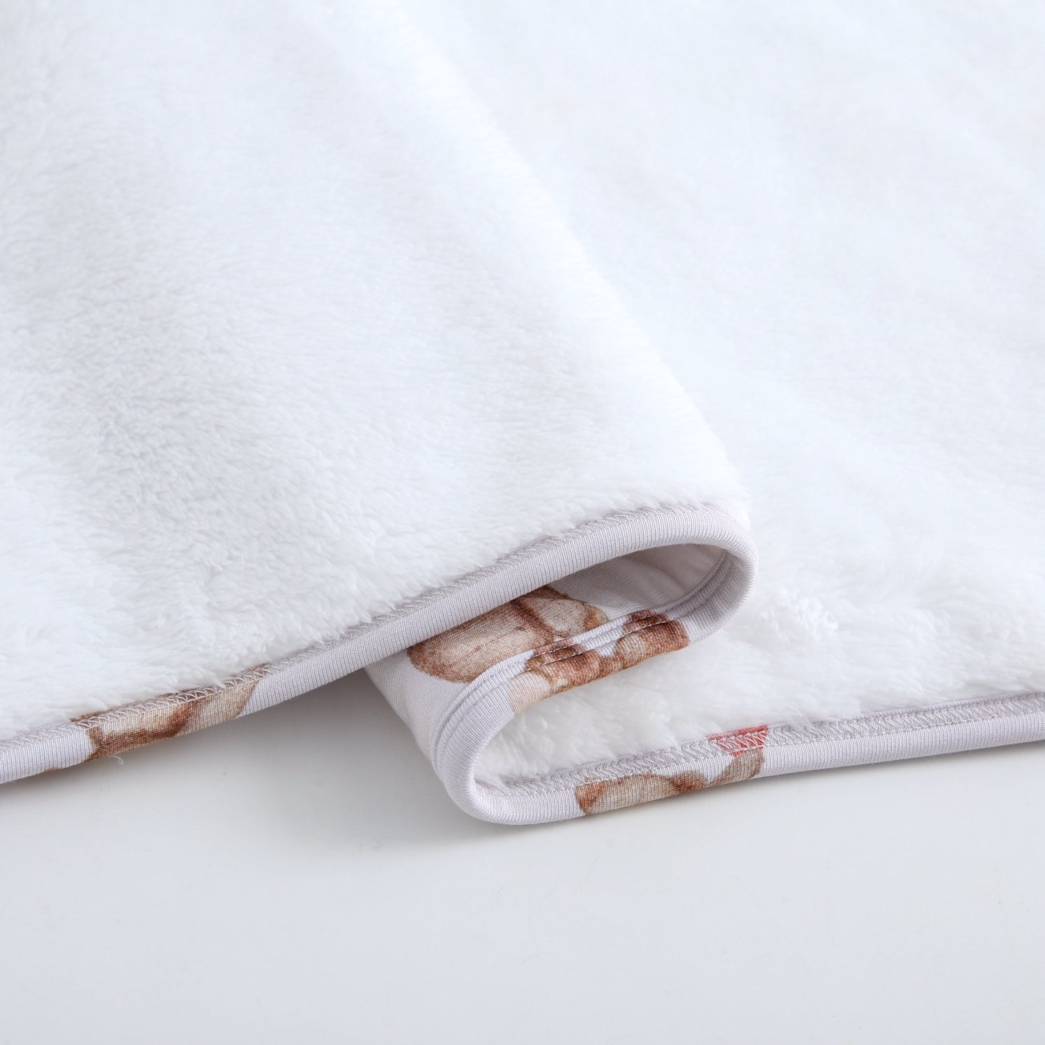 A white plush blanket with a teddy bear print on the trim.
