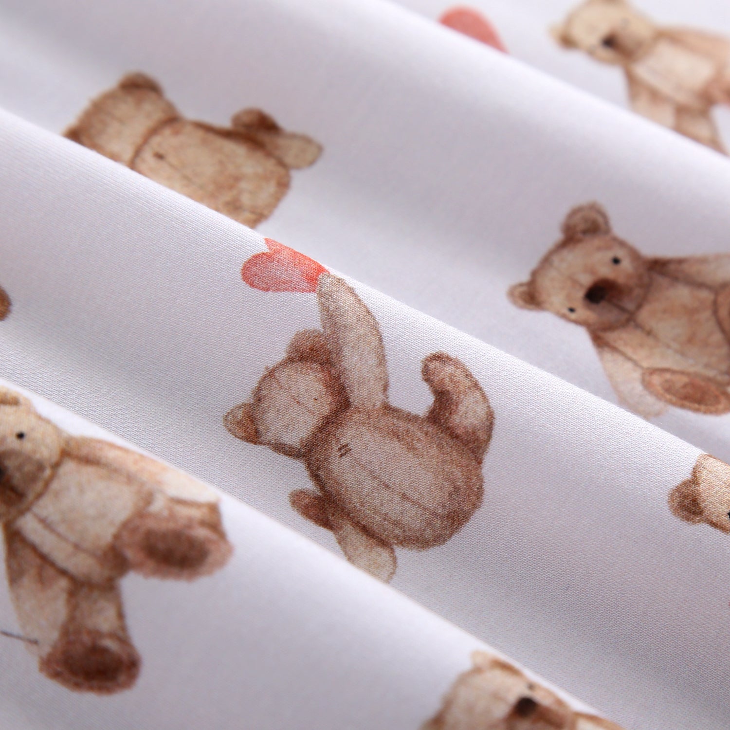 A white blanket with a pattern of watercolor teddy bears.
