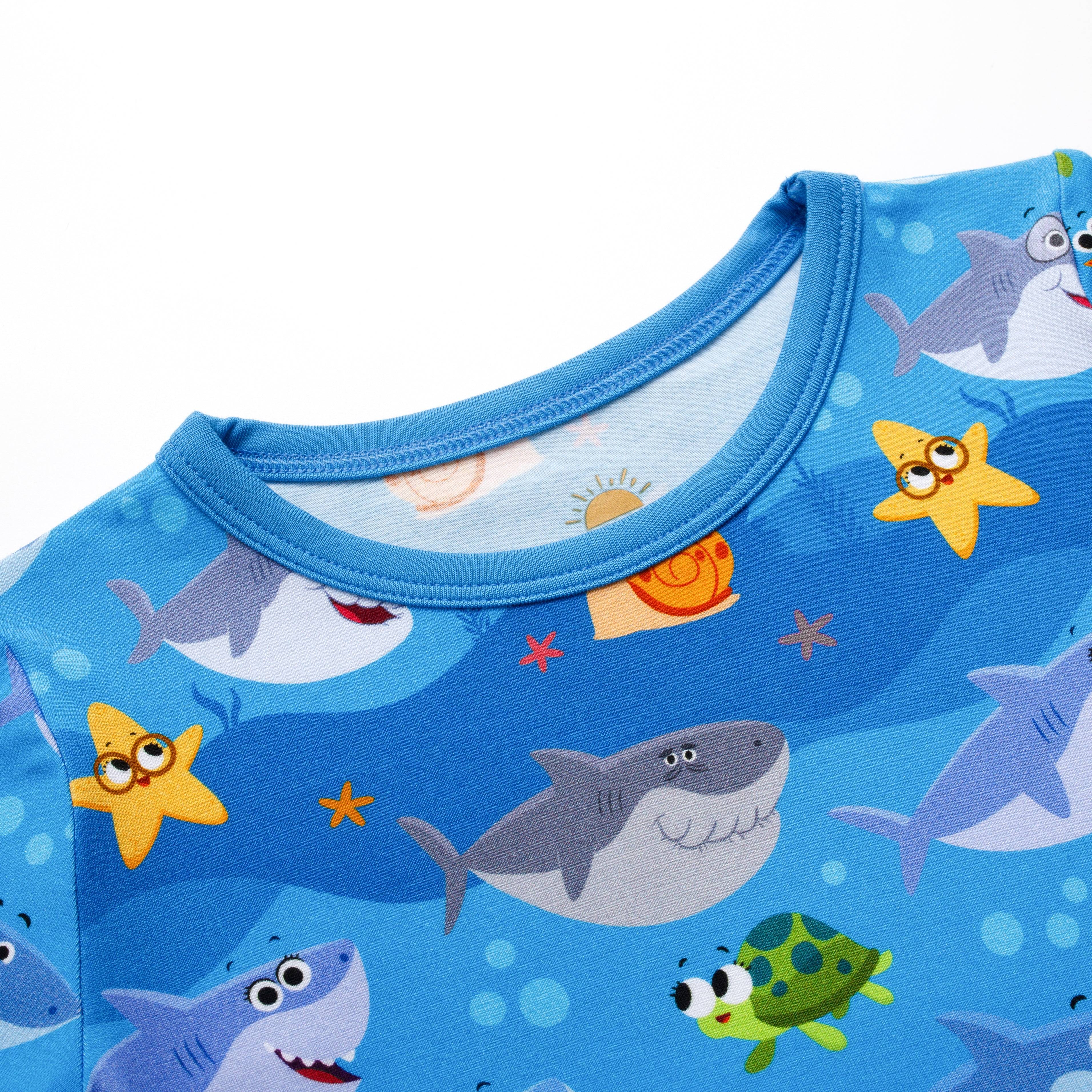 Blue pajama top with a repeating pattern of cartoon sharks, starfish, and a turtle.