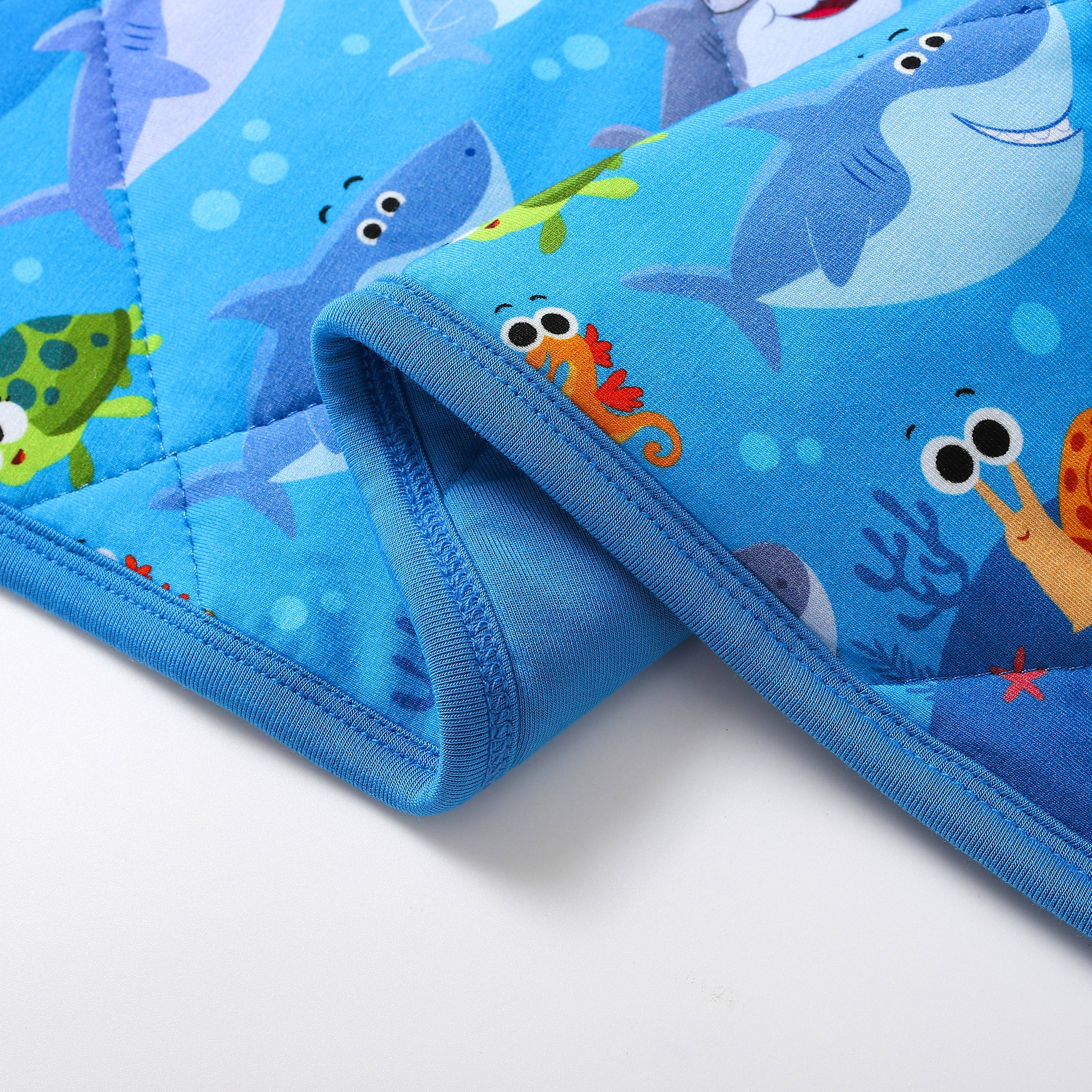 A blue quilted blanket with a Baby Shark print and ocean creatures.