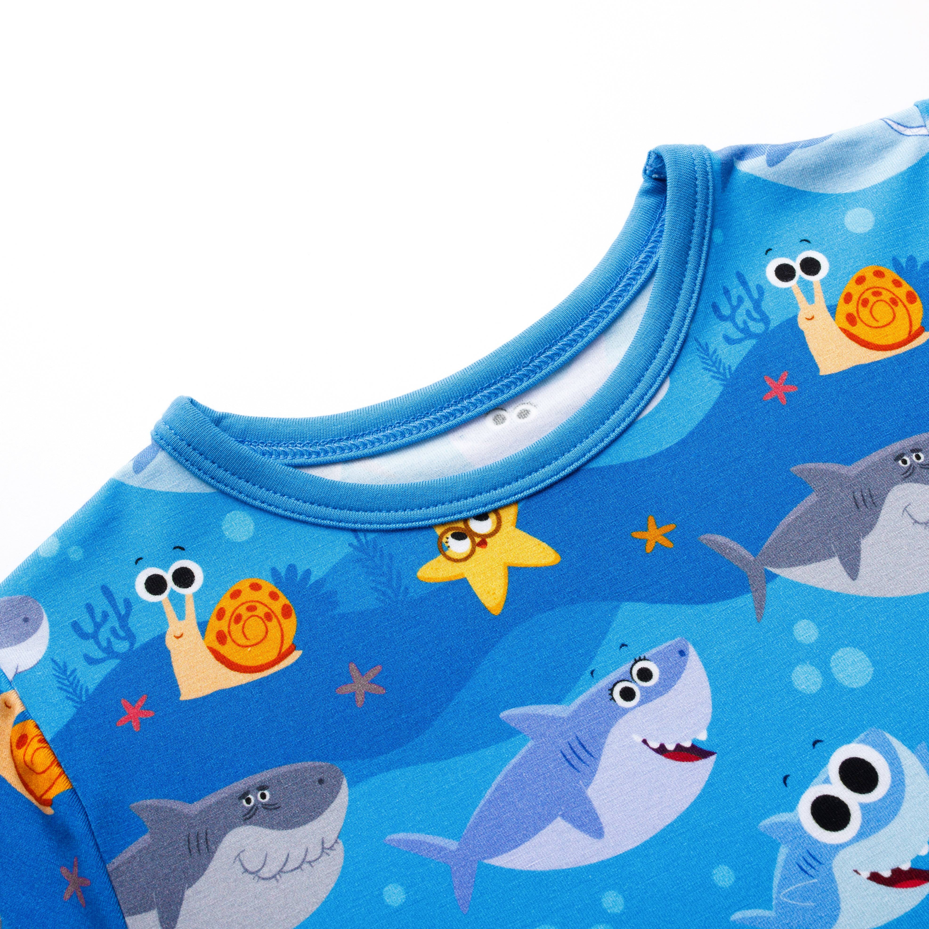 Blue t-shirt with a print of cartoon sharks, snails, and starfish.