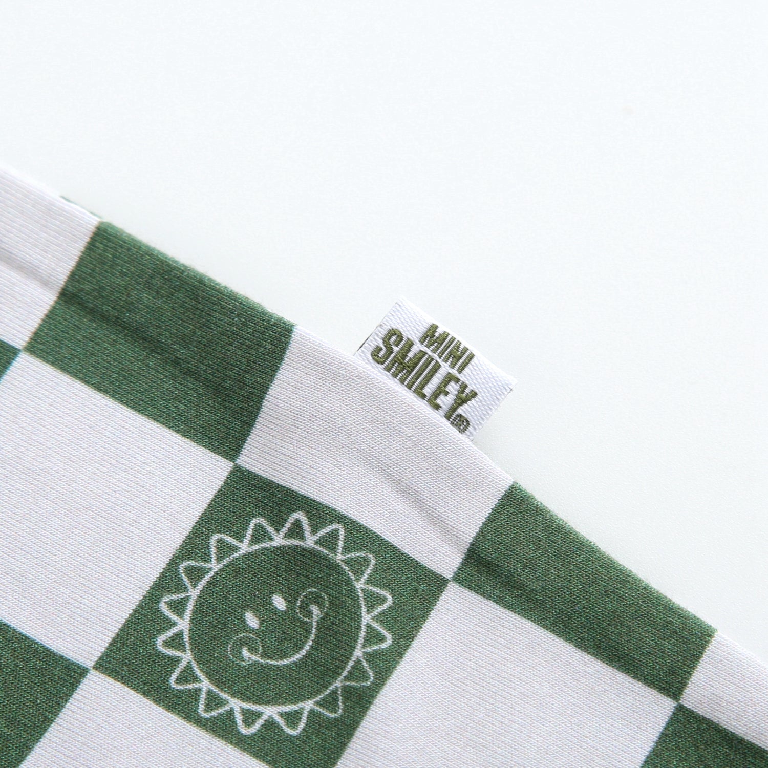 Overalls with a green and white checkerboard pattern and a Mini Smiley tag.