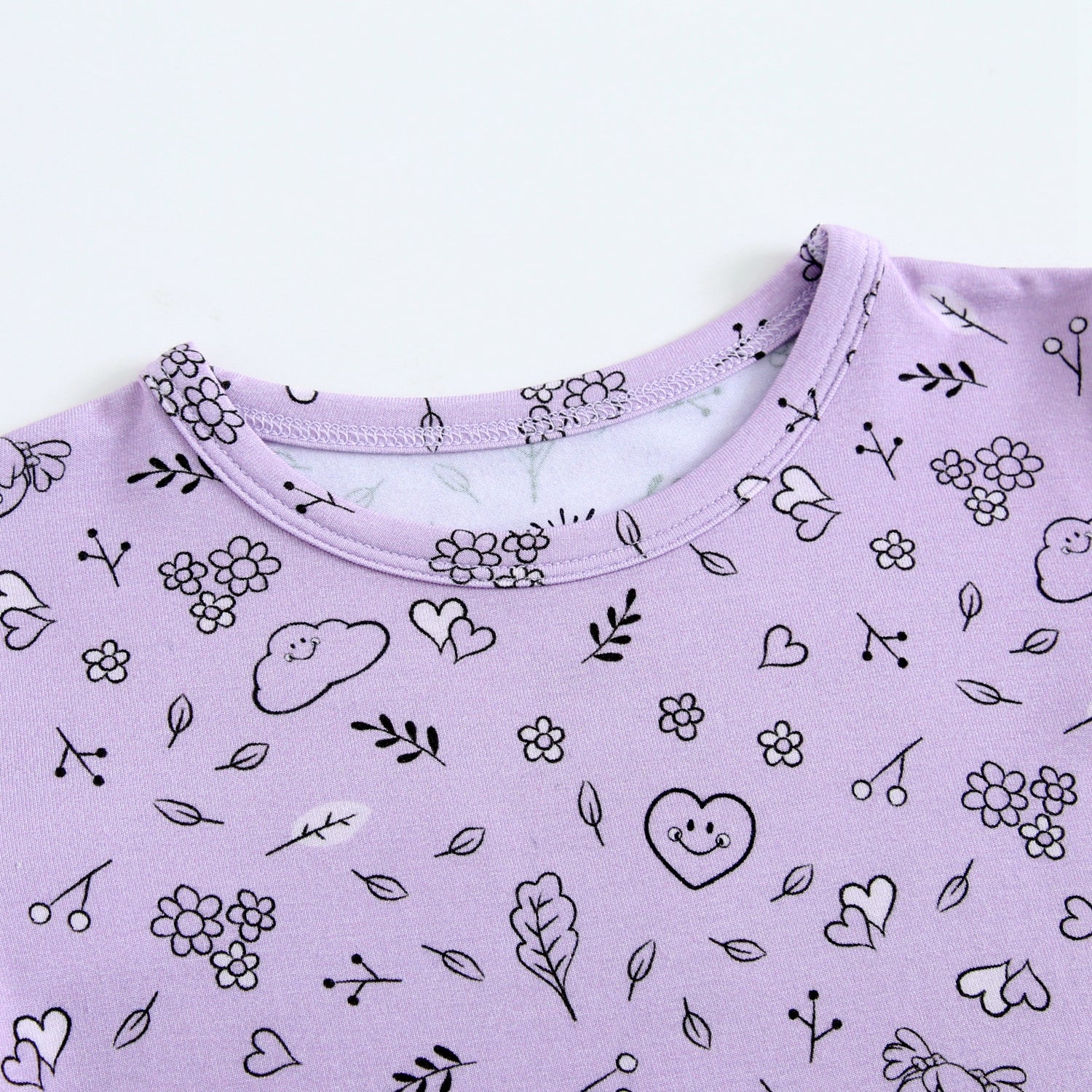 Lilac pajama set with a doodle print of flowers, hearts, and smiley faces.