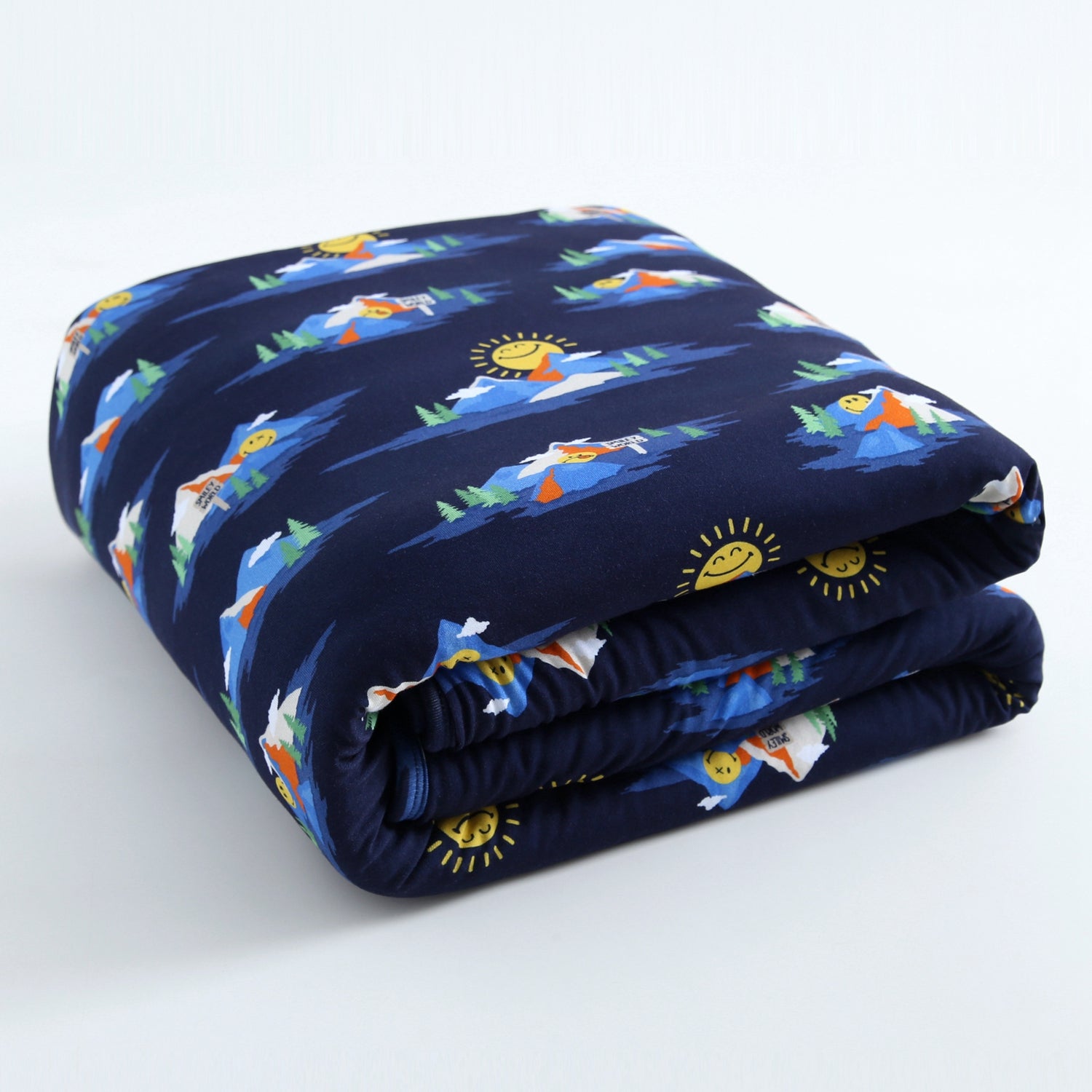 A navy blue blanket with a repeating pattern of mountains, trees, and smiling suns.