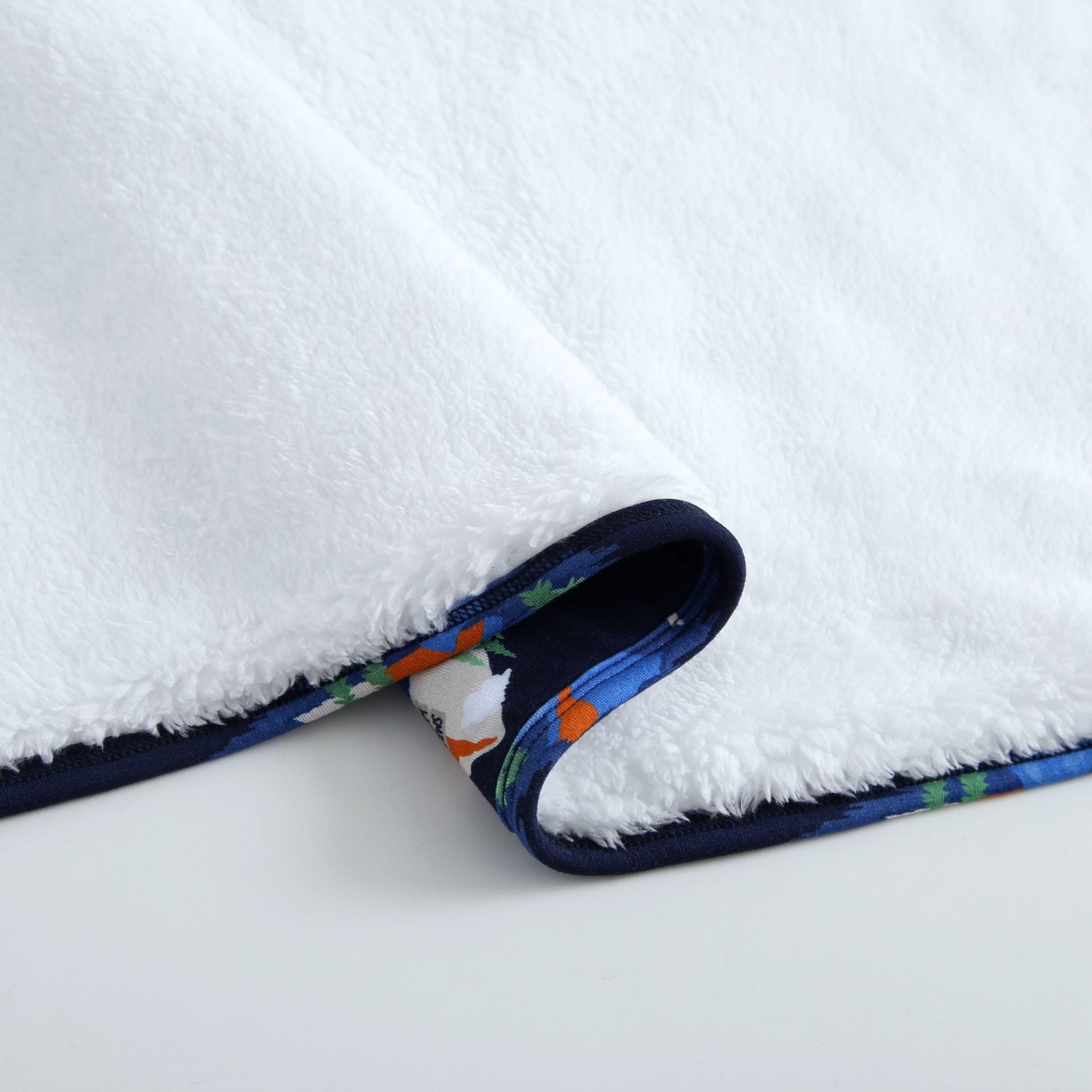 White plush blanket with a dark blue trim featuring a colorful SmileyWorld print.