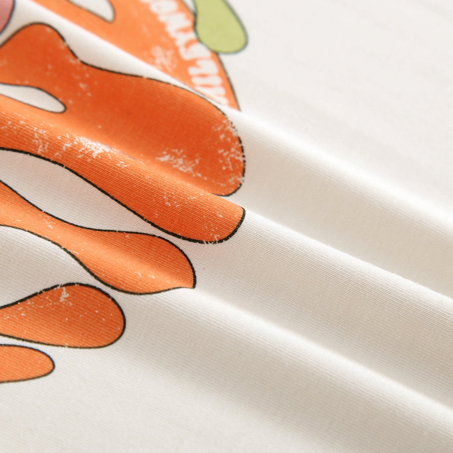 Close-up of a cream t-shirt with orange graphic elements.