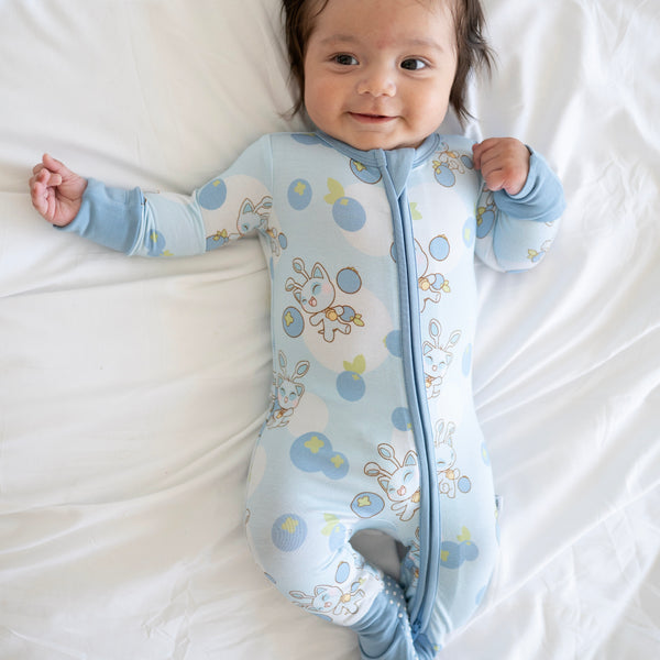 A baby wearing a light blue Neopets blueberry print zip-up pajama set.