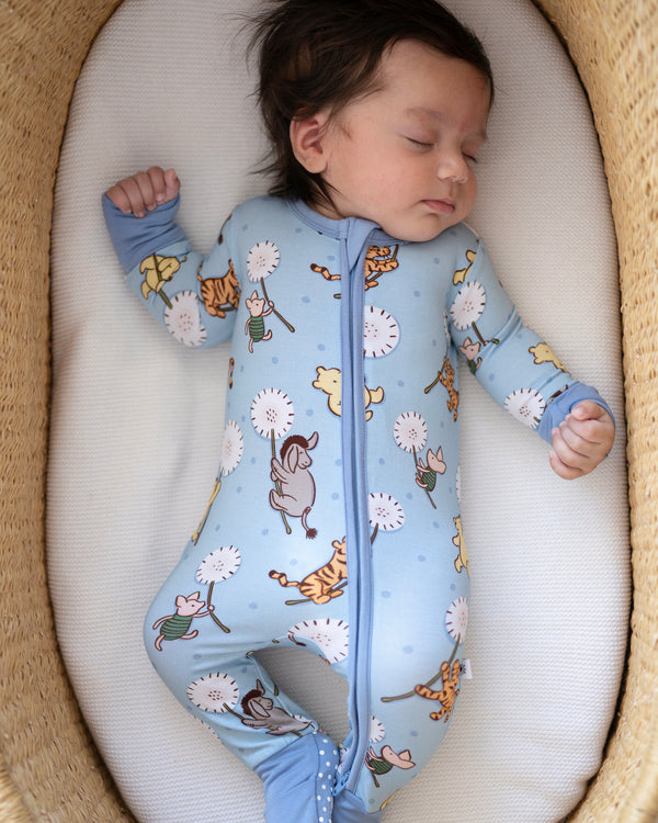 A baby sleeps in a blue pajama set with a Winnie the Pooh print.