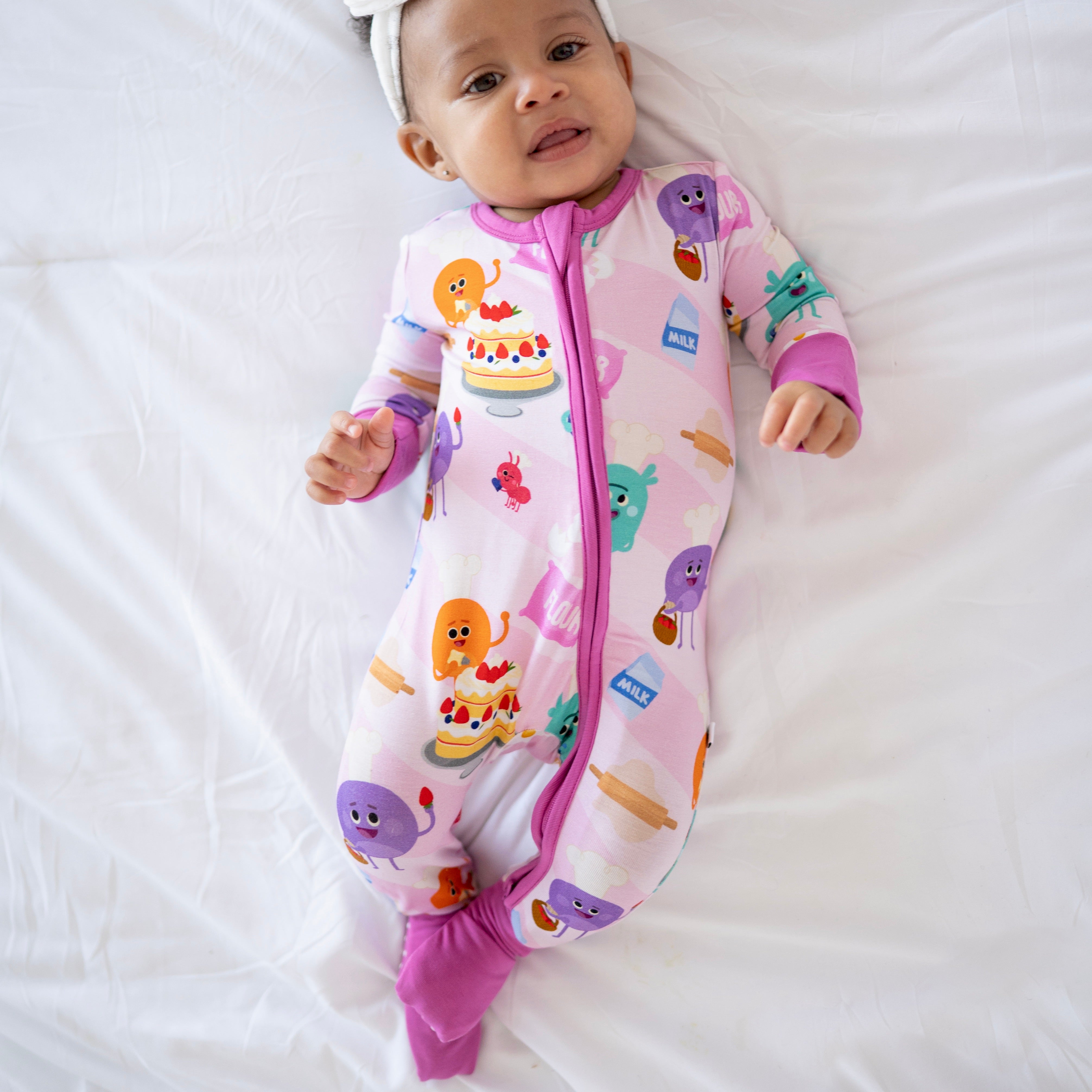 A baby wearing a pink bamboo pajama set with a baking-themed print.