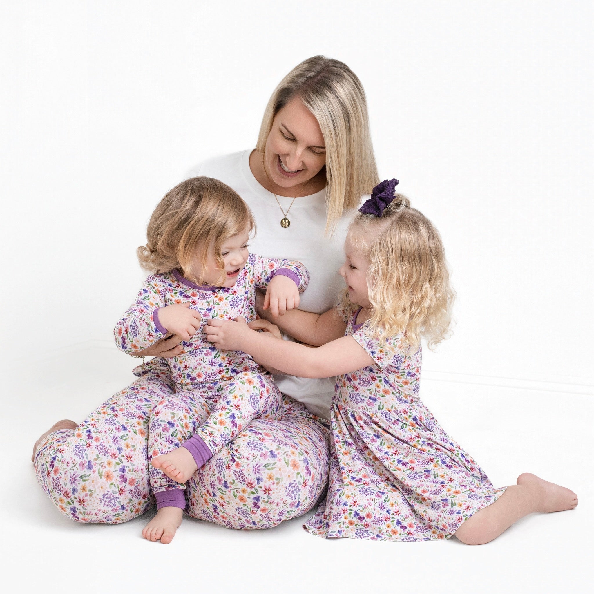 A mother and two daughters in matching floral pajamas.