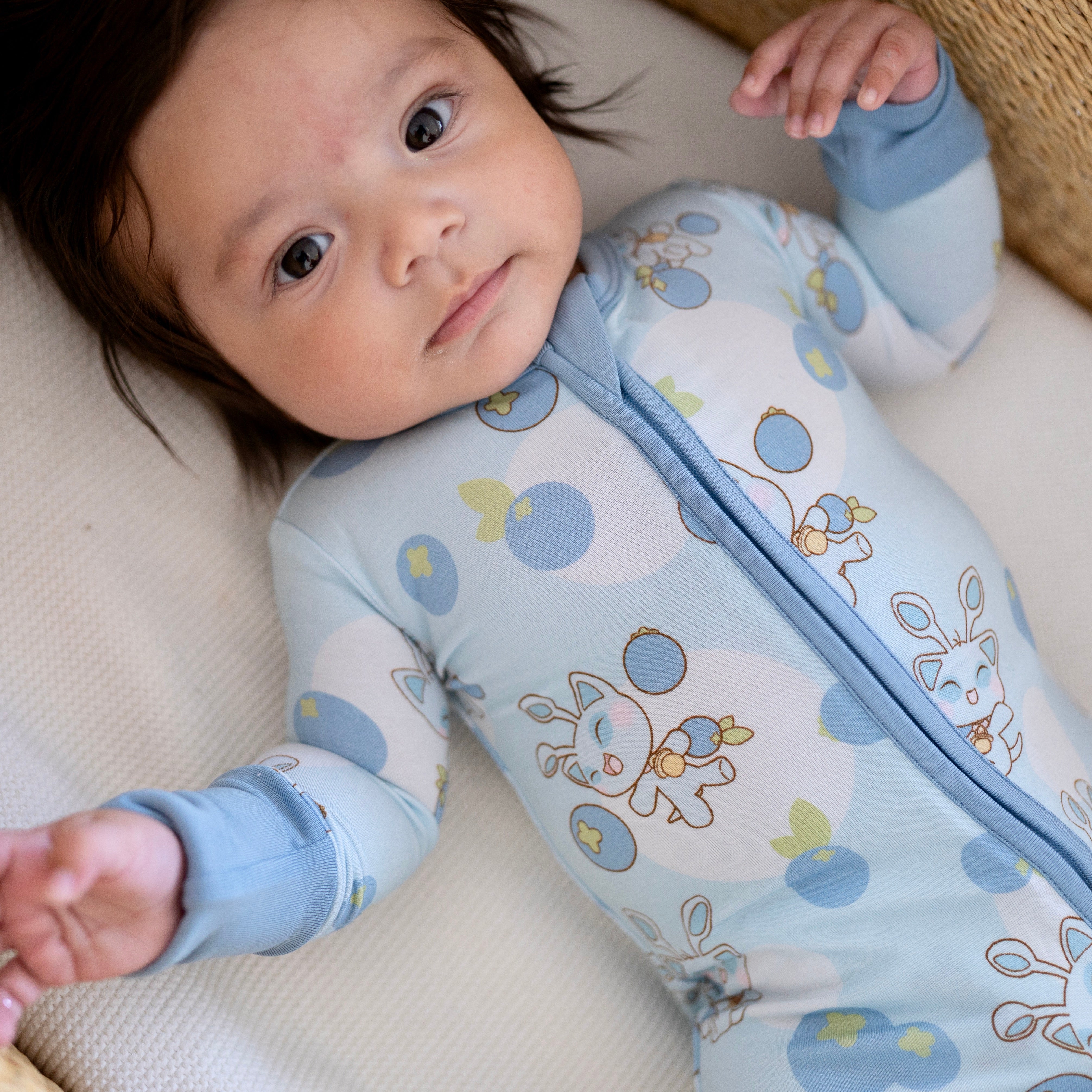 Baby in a light blue Neopets blueberry print zip-up pajama.